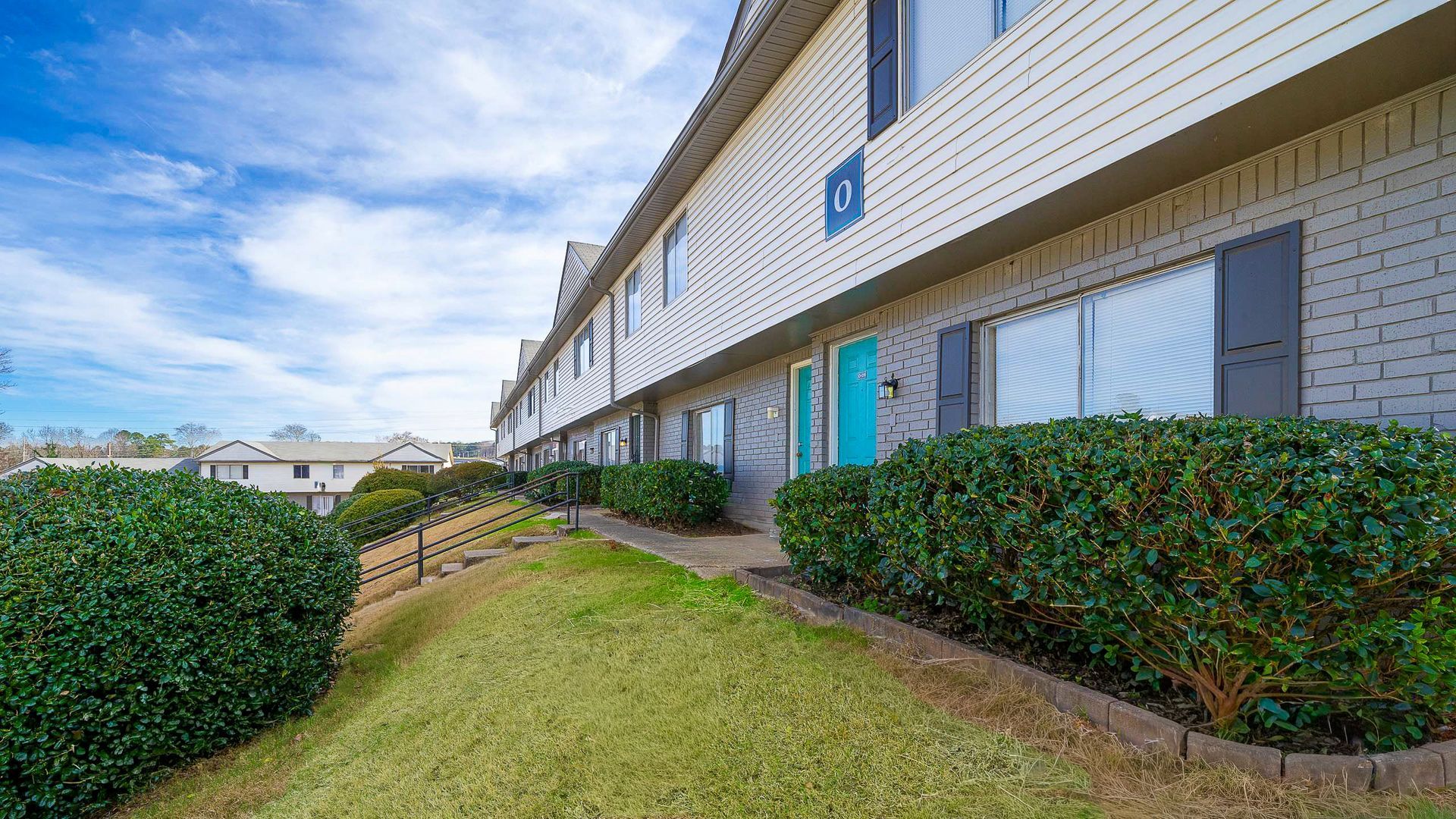 Apartment buildings on a grassy hill. Blue door stands out. Overcast sky.