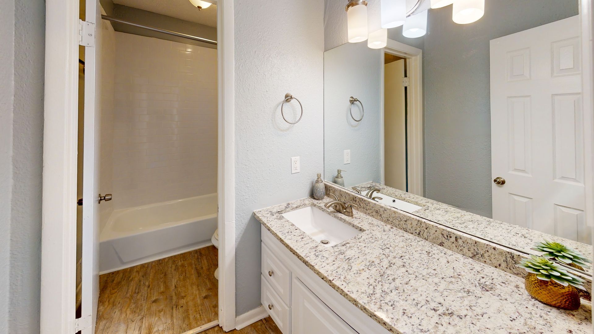 Bathroom with white cabinets, granite countertop, and bathtub.