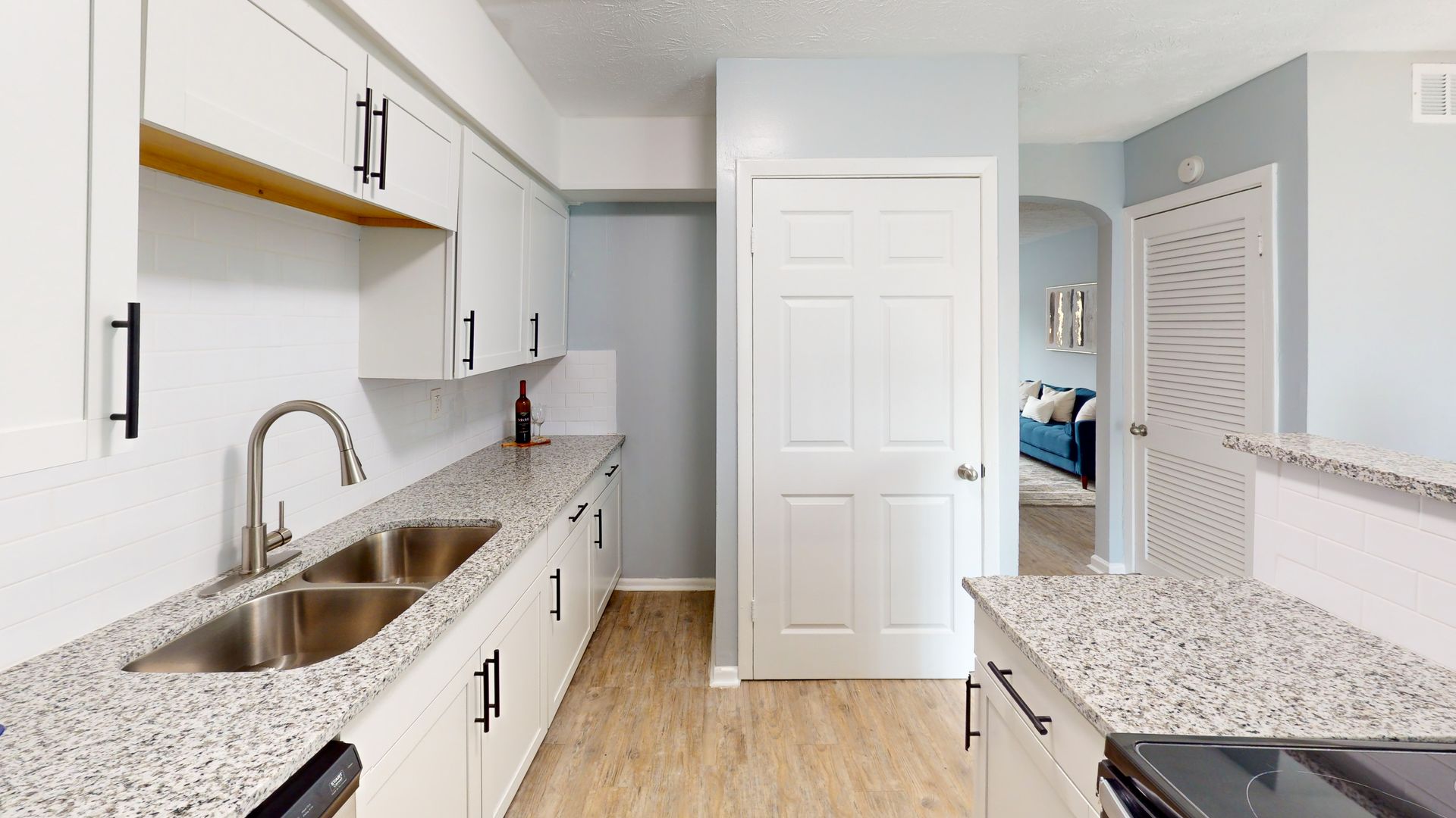 Kitchen with white cabinets, granite countertops, stainless steel appliances, and white subway tile backsplash.