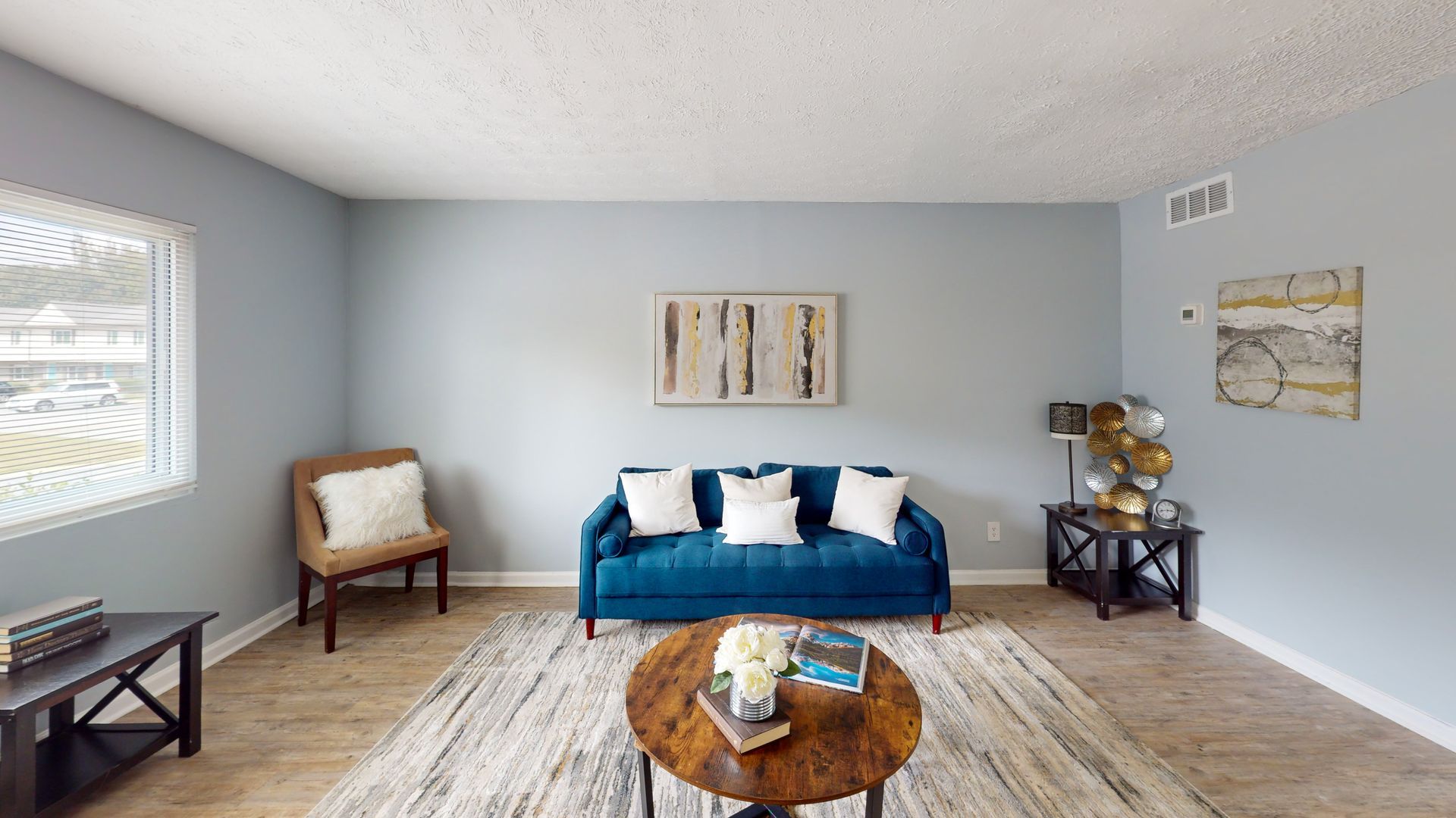 Empty apartment room with sliding glass door to a small deck; white walls, kitchen visible.