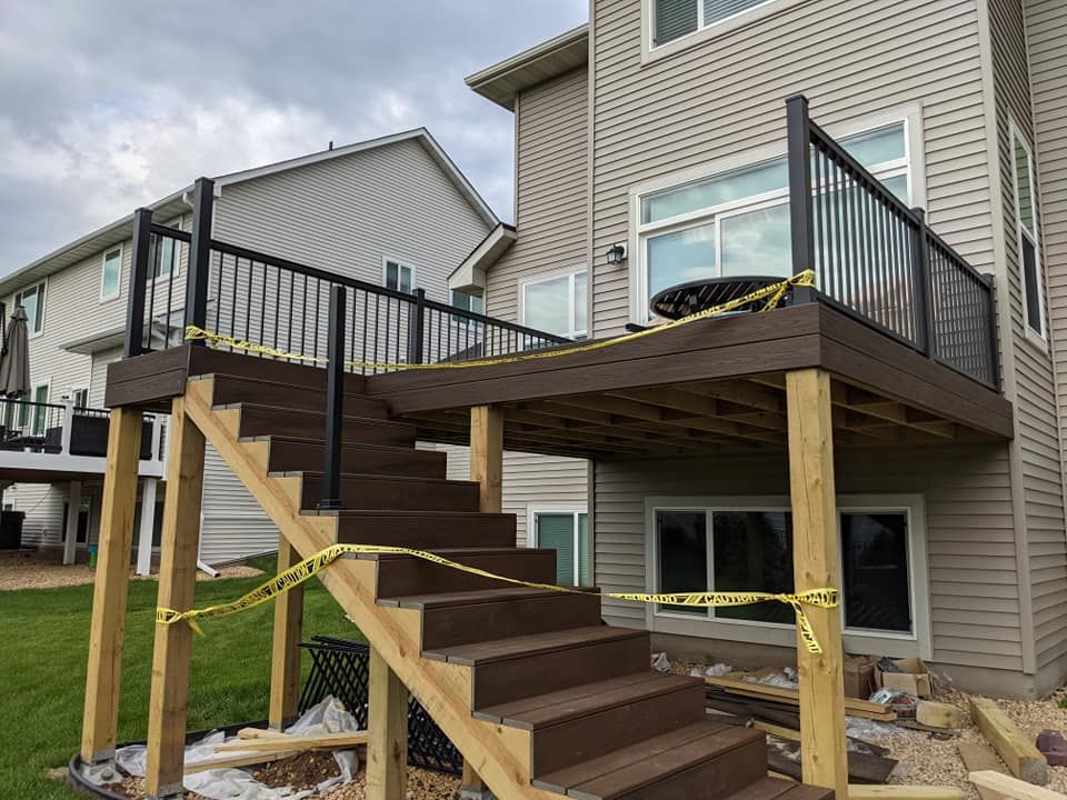 A wooden deck with stairs leading up to it is being built in front of a house.