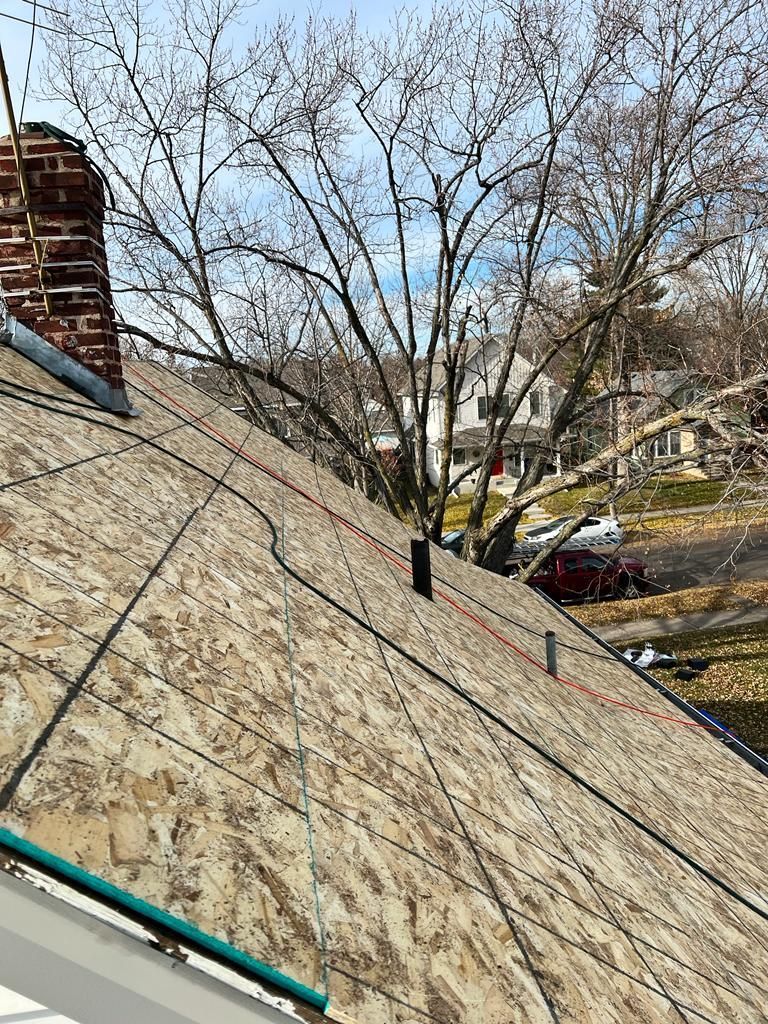 A close up of a roof with a chimney and trees in the background.