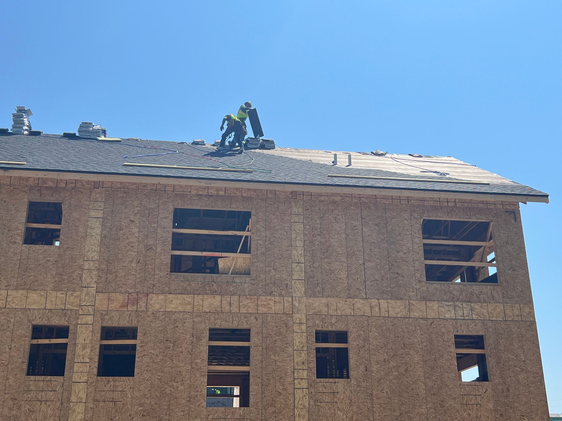 Two men are working on the roof of a house under construction