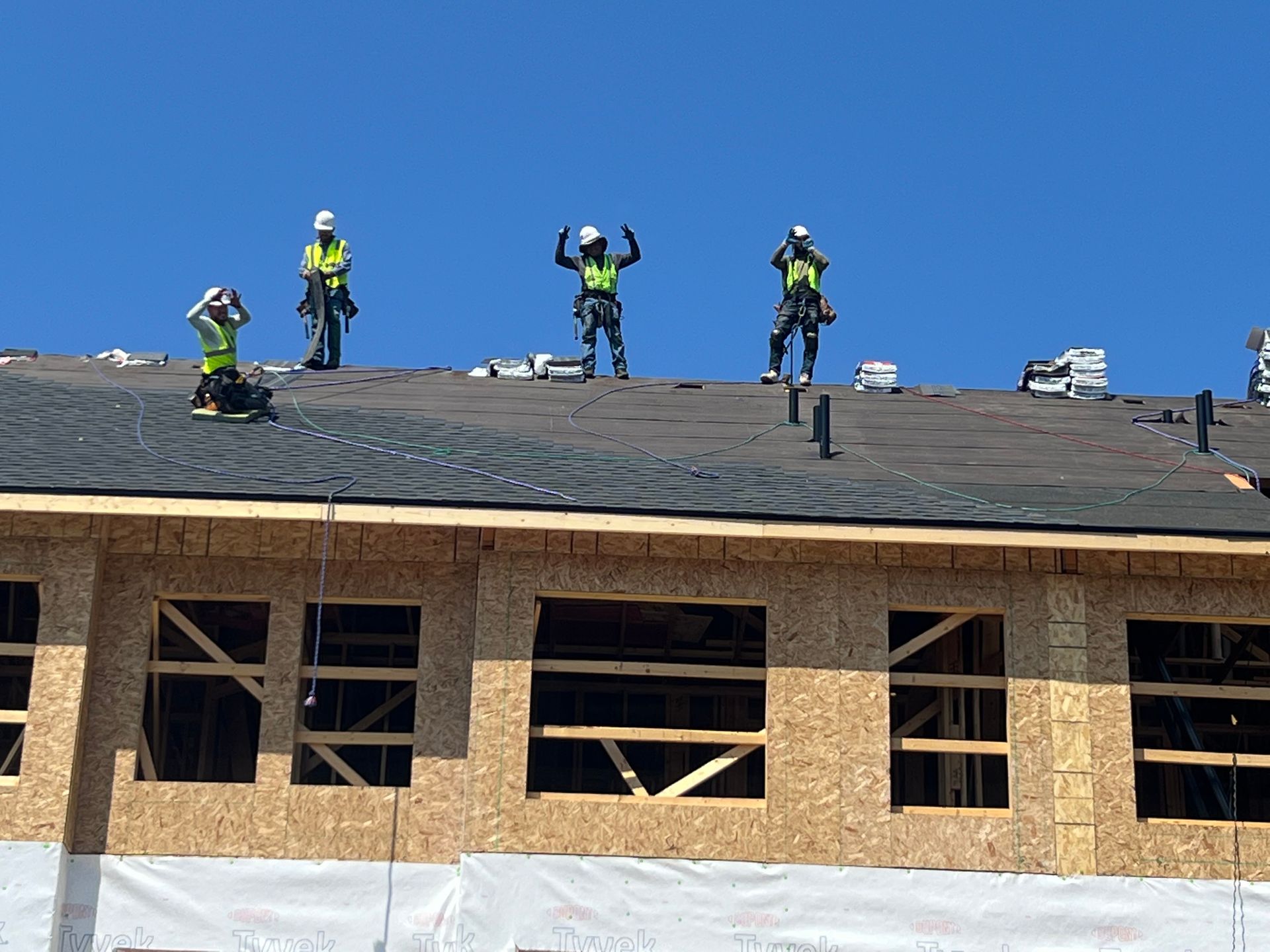 A group of construction workers are working on the roof of a building