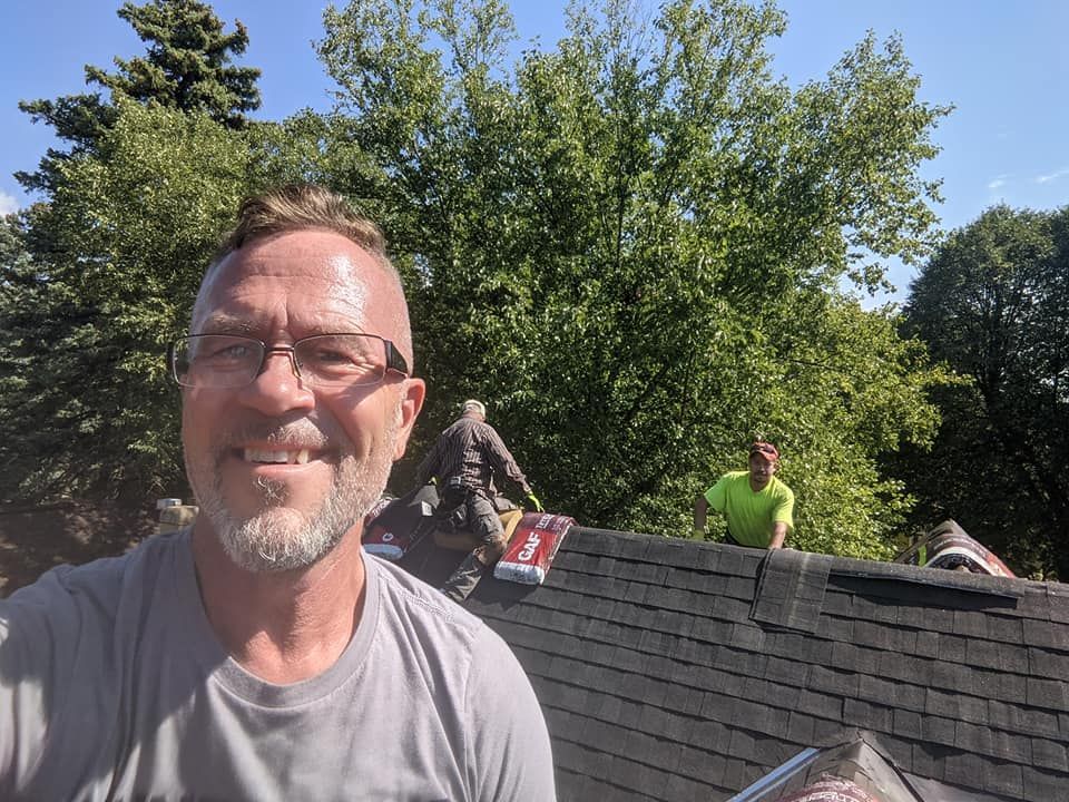 A man with glasses is standing on top of a roof.
