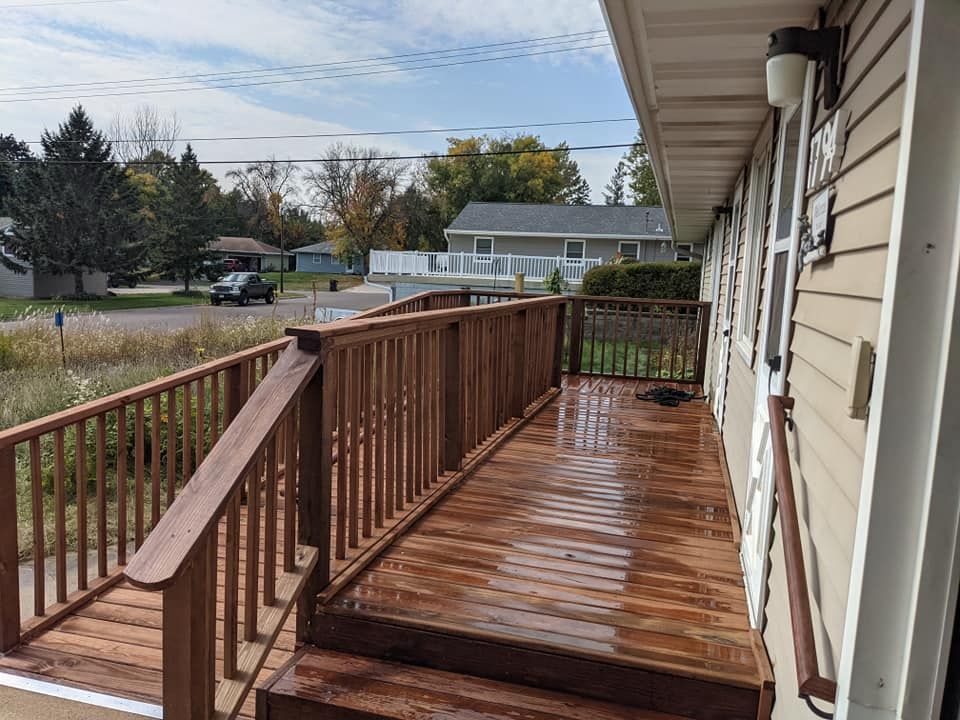 A wooden deck with stairs and a railing on the side of a house.