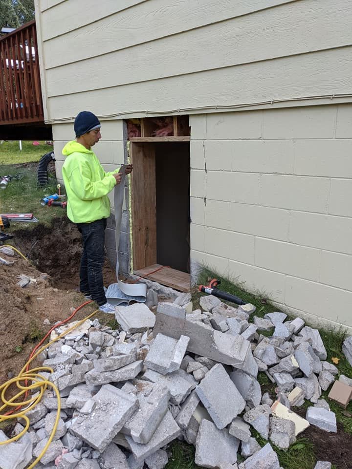 A man is standing next to a pile of bricks in front of a house.