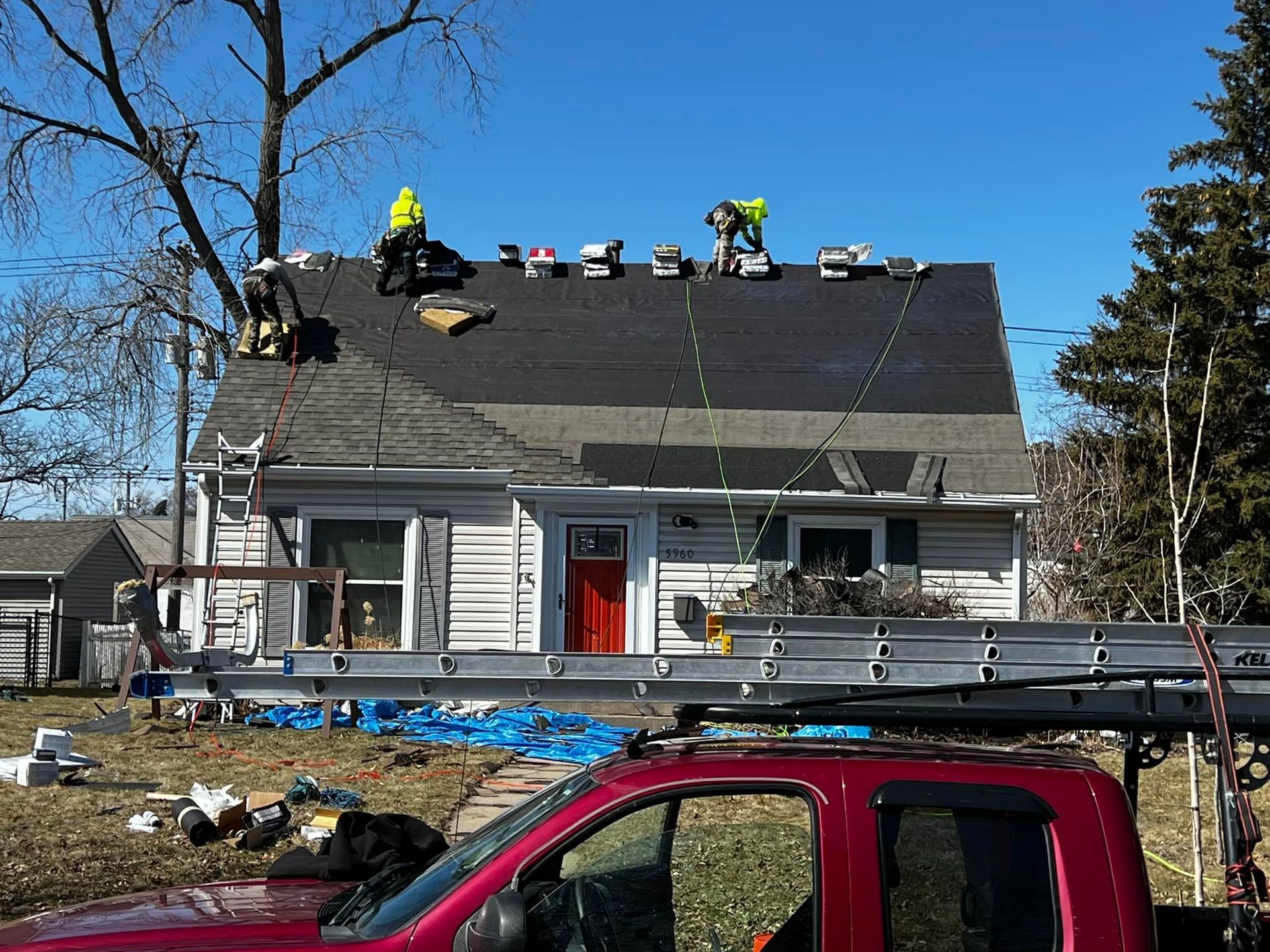 A red truck is parked in front of a house that is being remodeled.