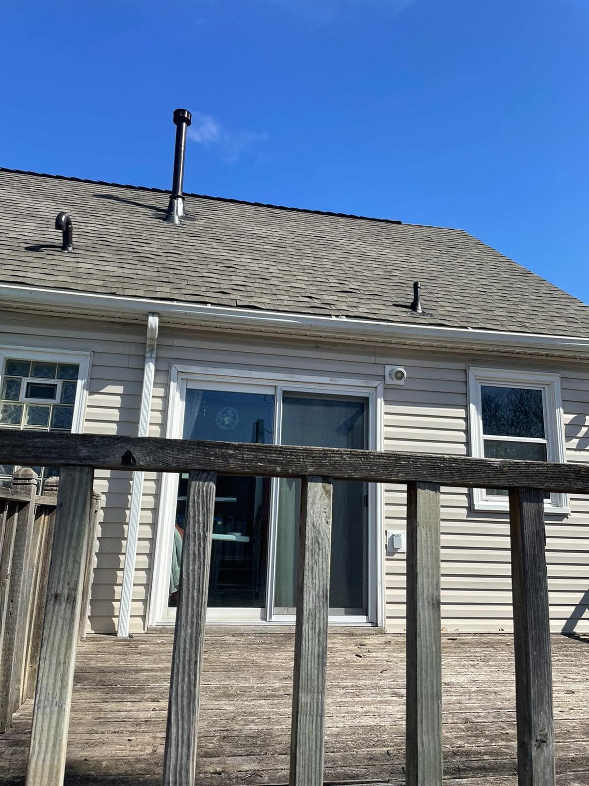 The back of a house with a wooden deck and a sliding glass door.
