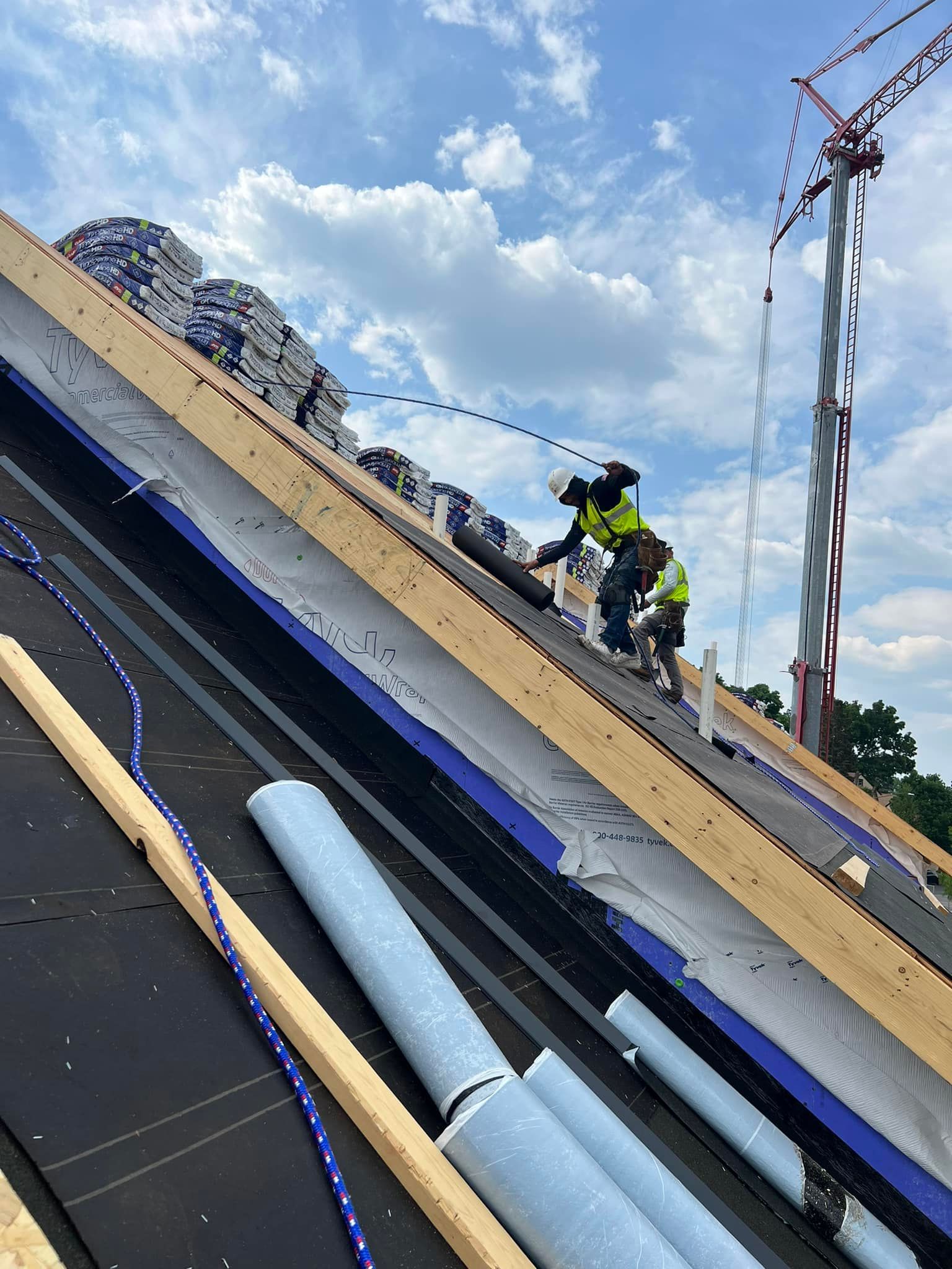 A man is working on a roof with a crane in the background.