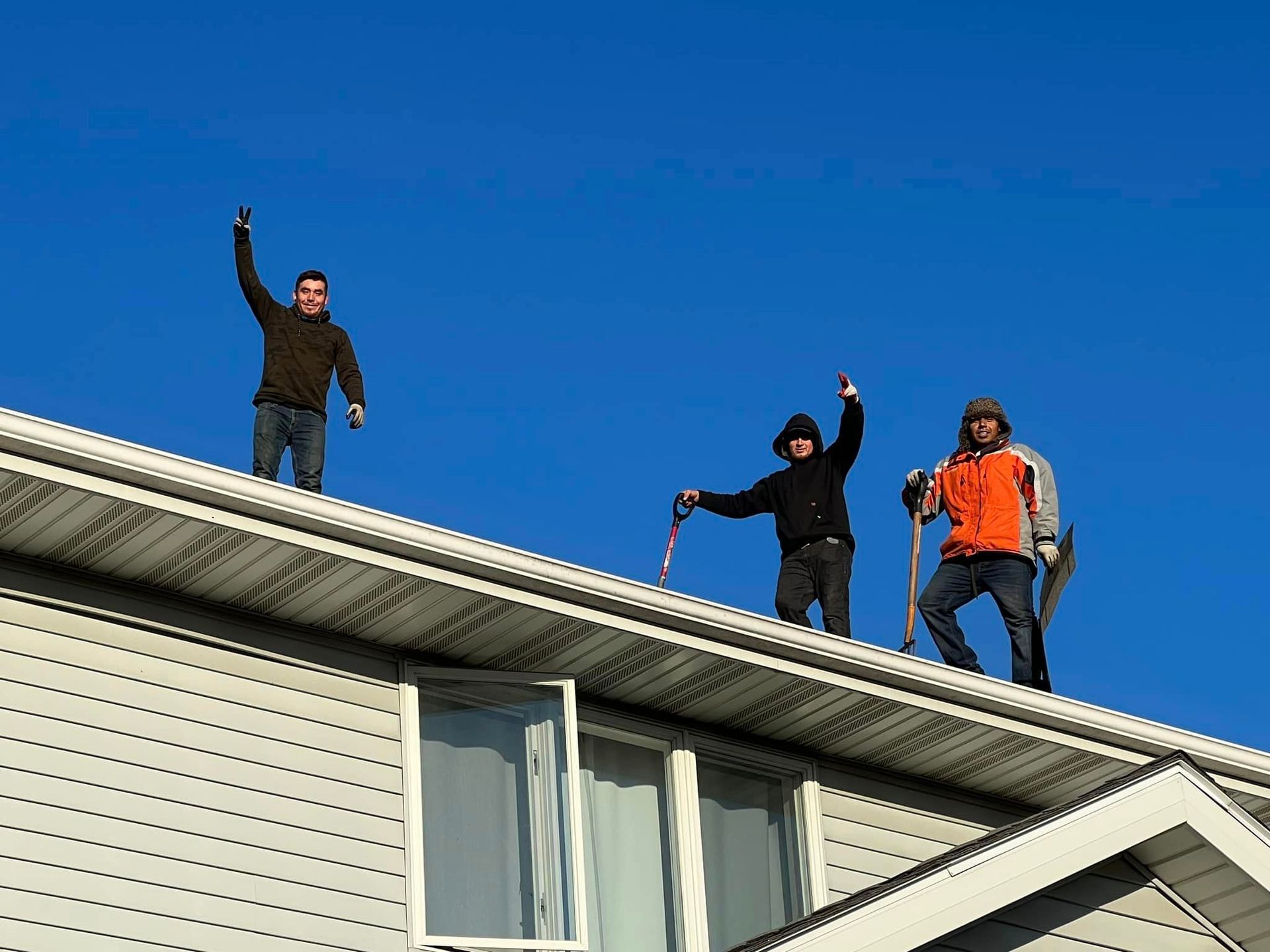 Three men are standing on the roof of a house.