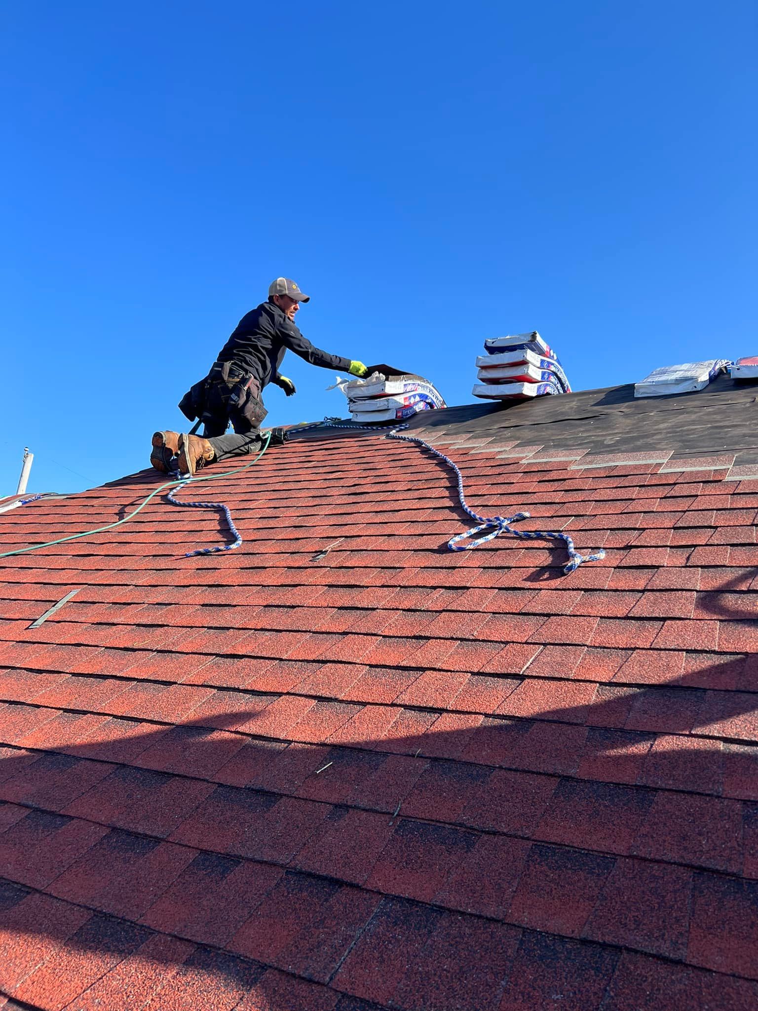 A man is standing on top of a red roof.