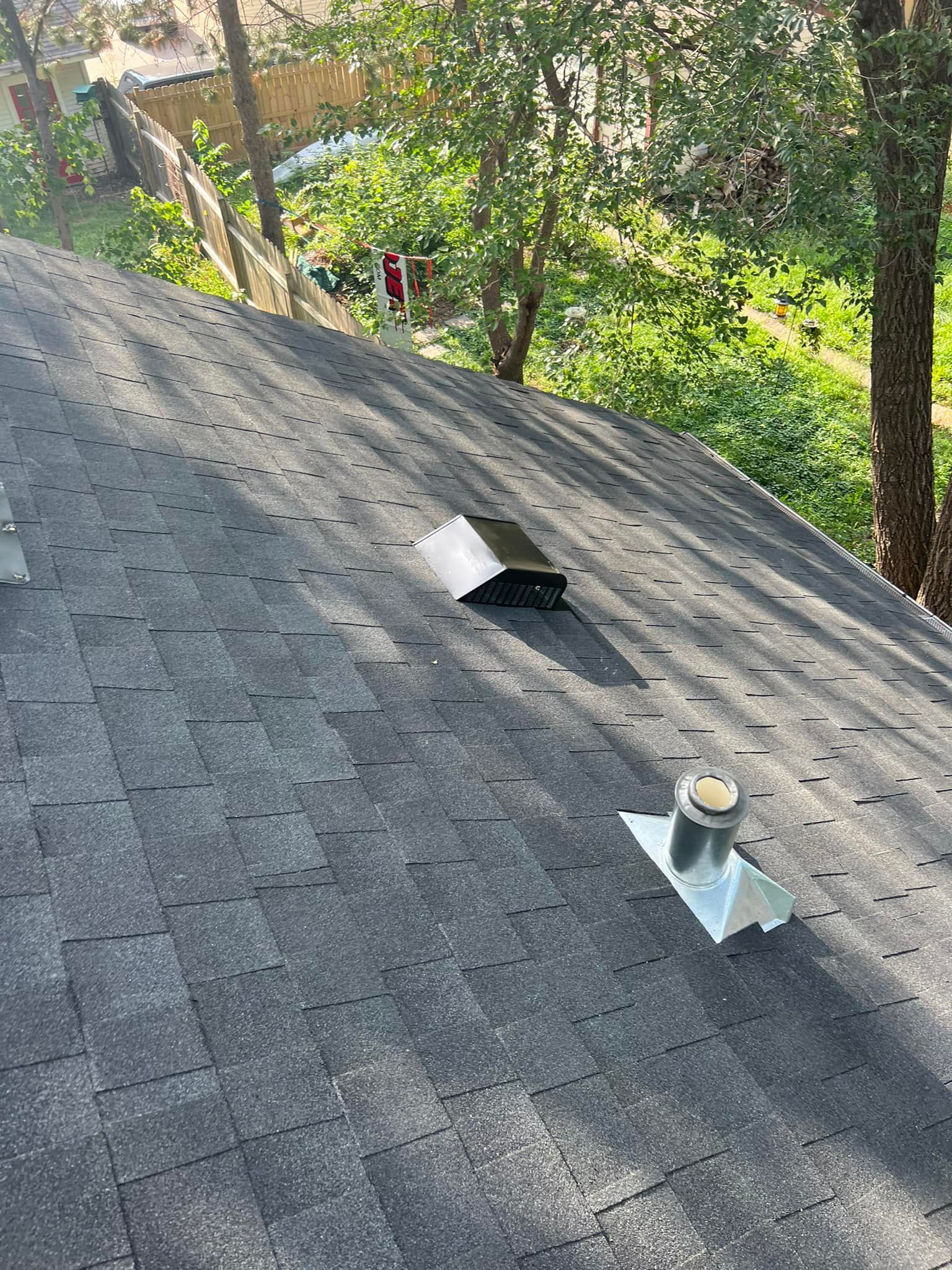 A roof with a chimney on it and trees in the background.