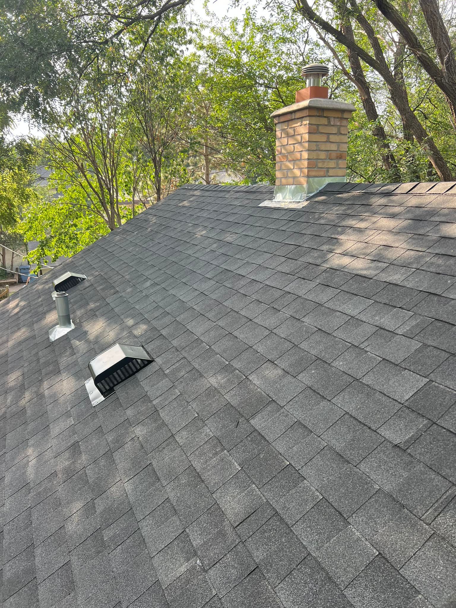 A roof with a chimney on top of it and trees in the background.