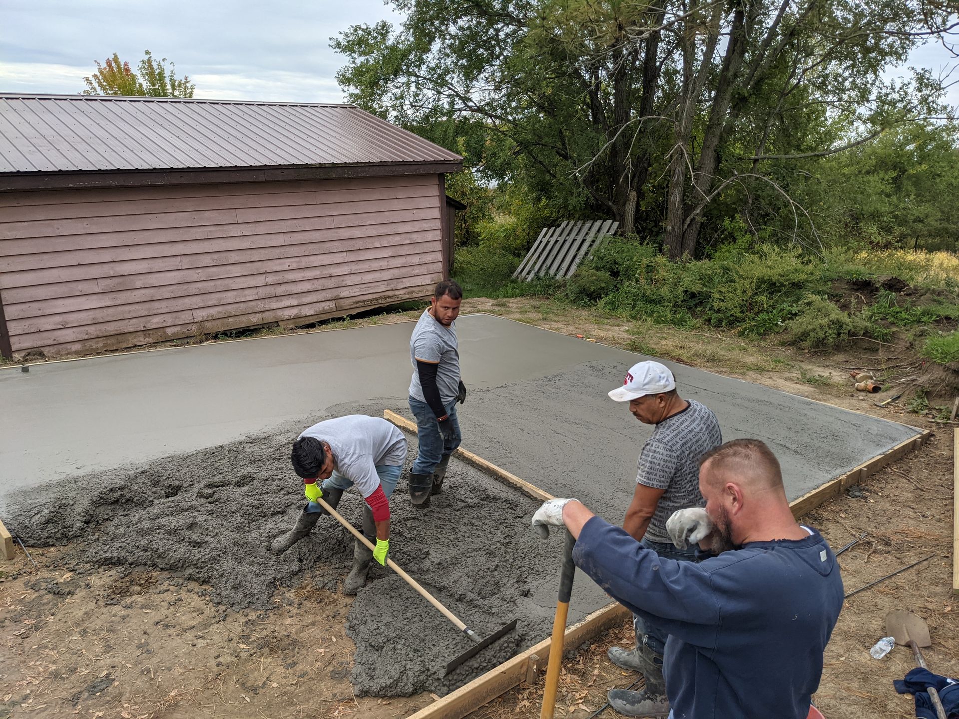 A group of men are working on a concrete driveway.