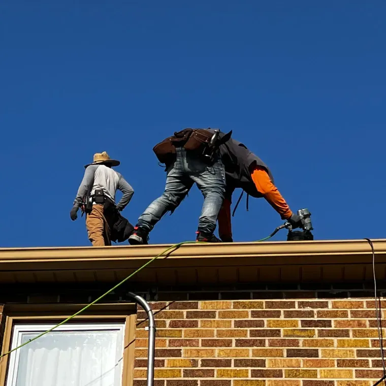 Two men are working on the roof of a brick building