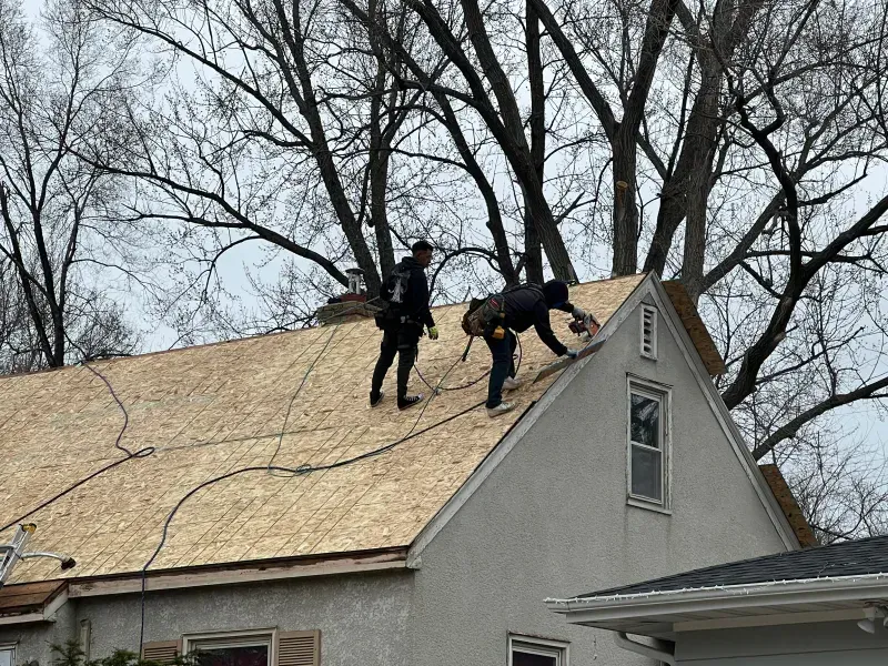 Two men are working on the roof of a house.