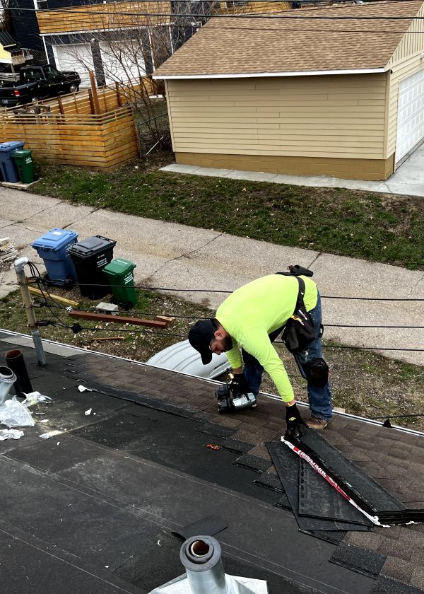 A man in a neon yellow shirt is working on a roof.