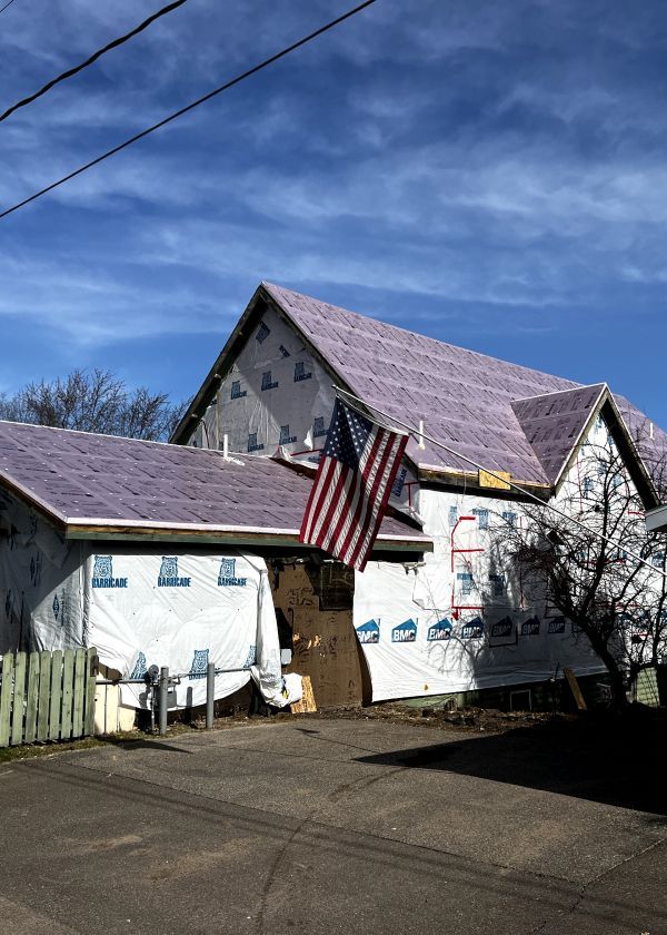 A house under construction with an american flag hanging from the roof.