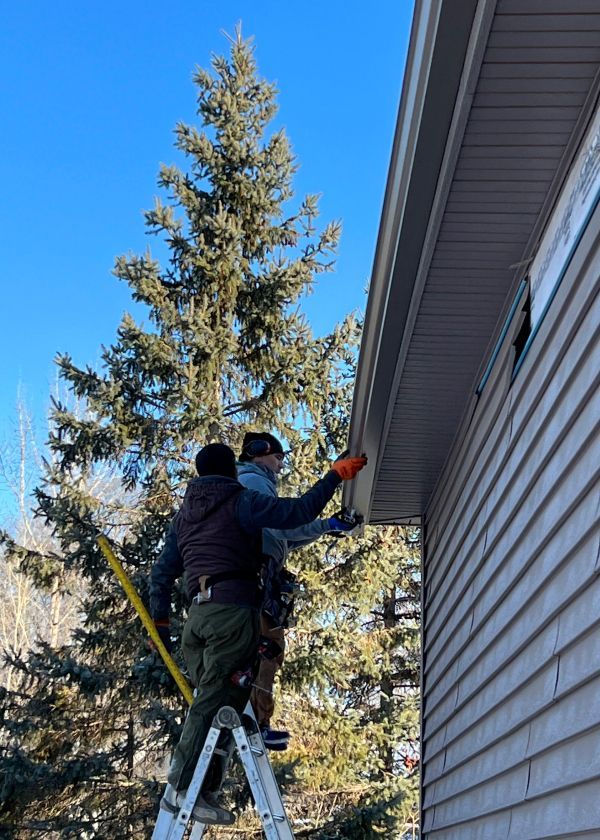 Two men are working on the side of a house.