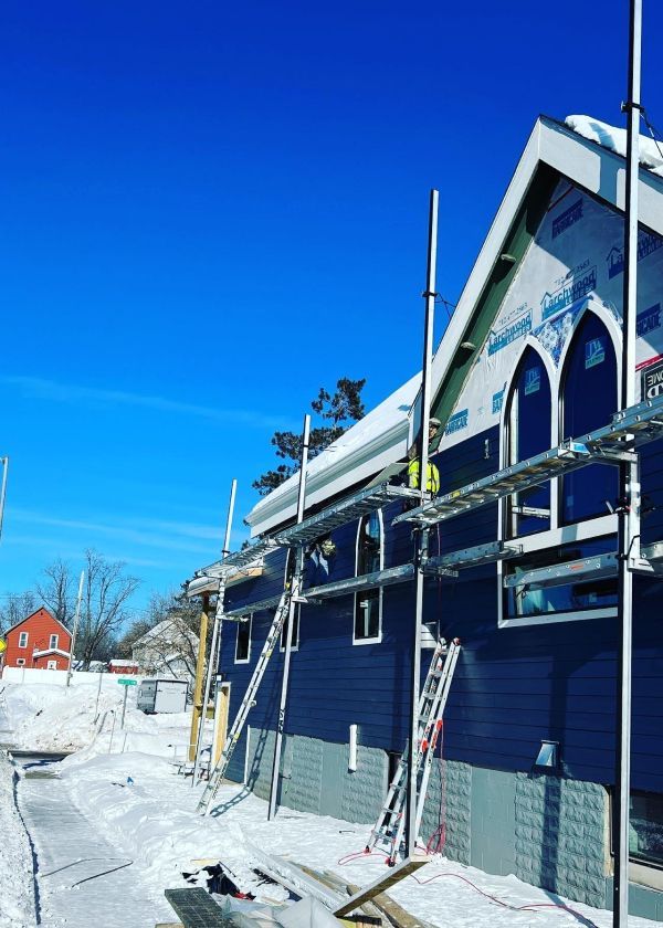 A blue building with scaffolding around it is being built in the snow.