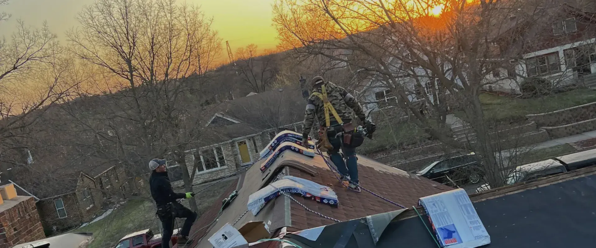 A group of people are working on a roof at sunset.