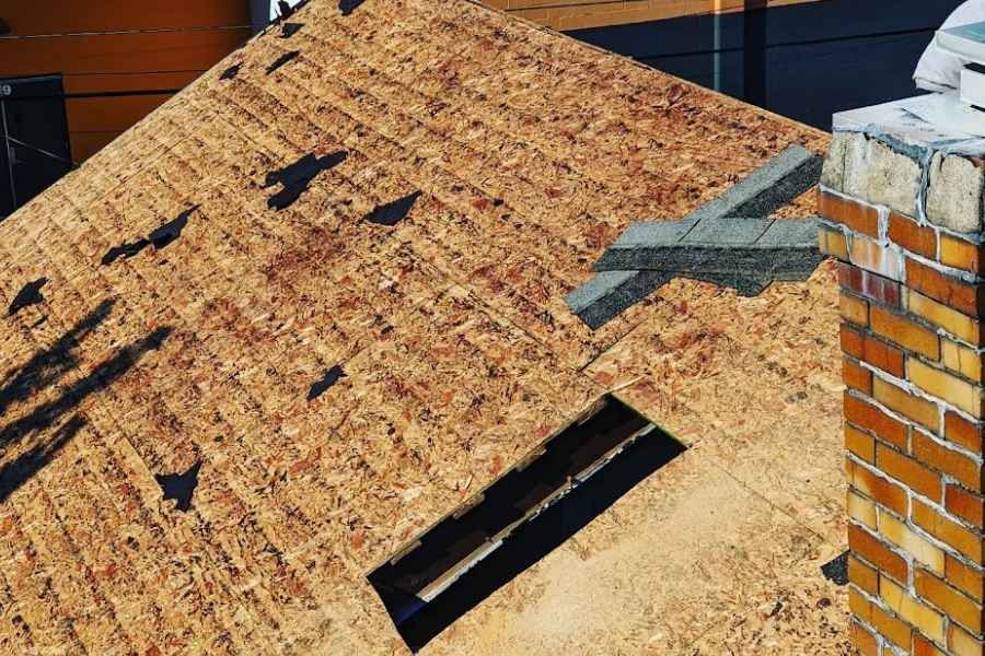 A close up of a roof with a chimney in the background.