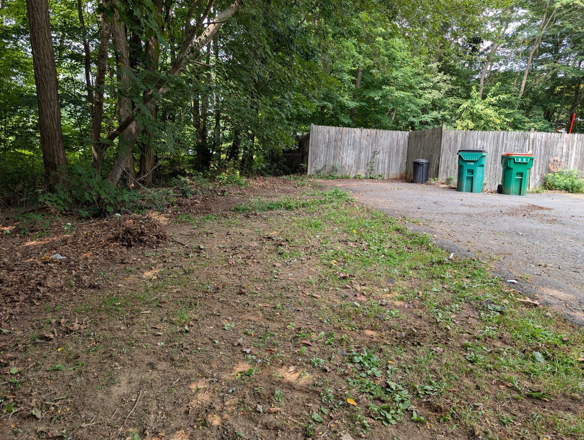 Snowy ground with a dark plastic bag, patches of dirt, and a building's white side.