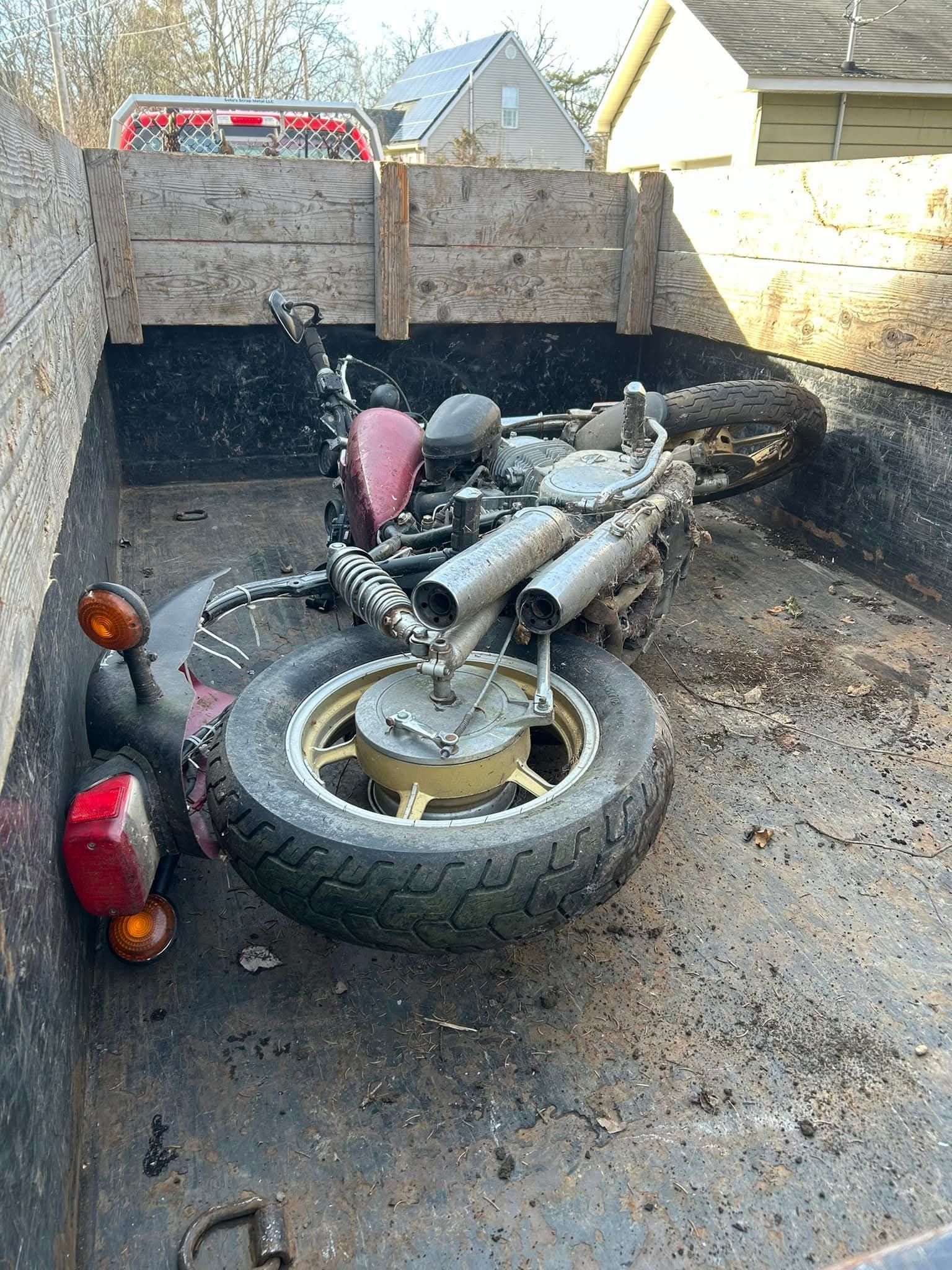 Motorcycle in a truck bed, red and black, partially disassembled.