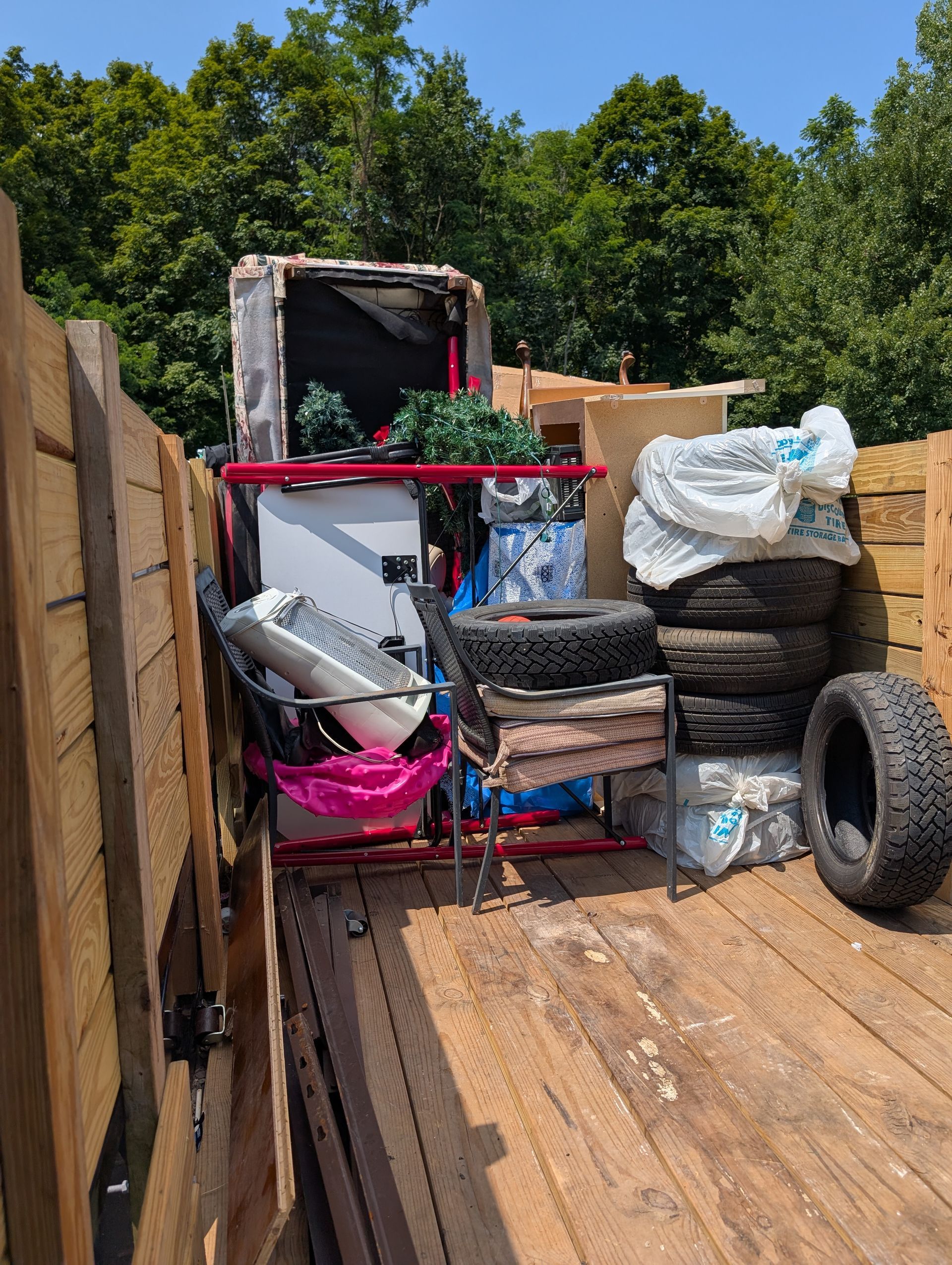 Truck bed loaded with items: tires, furniture, and miscellaneous debris.