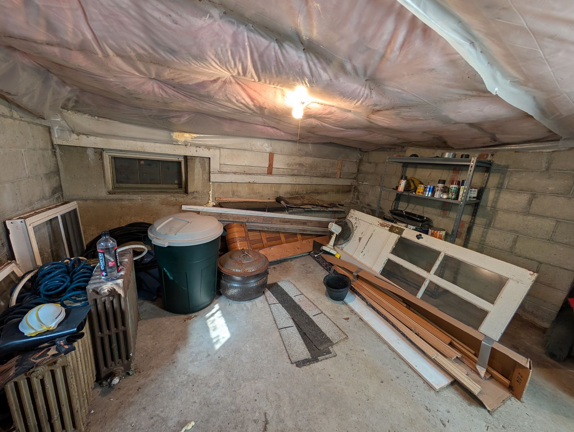 Cluttered basement with exposed cinder block walls, various objects, and a bare lightbulb.