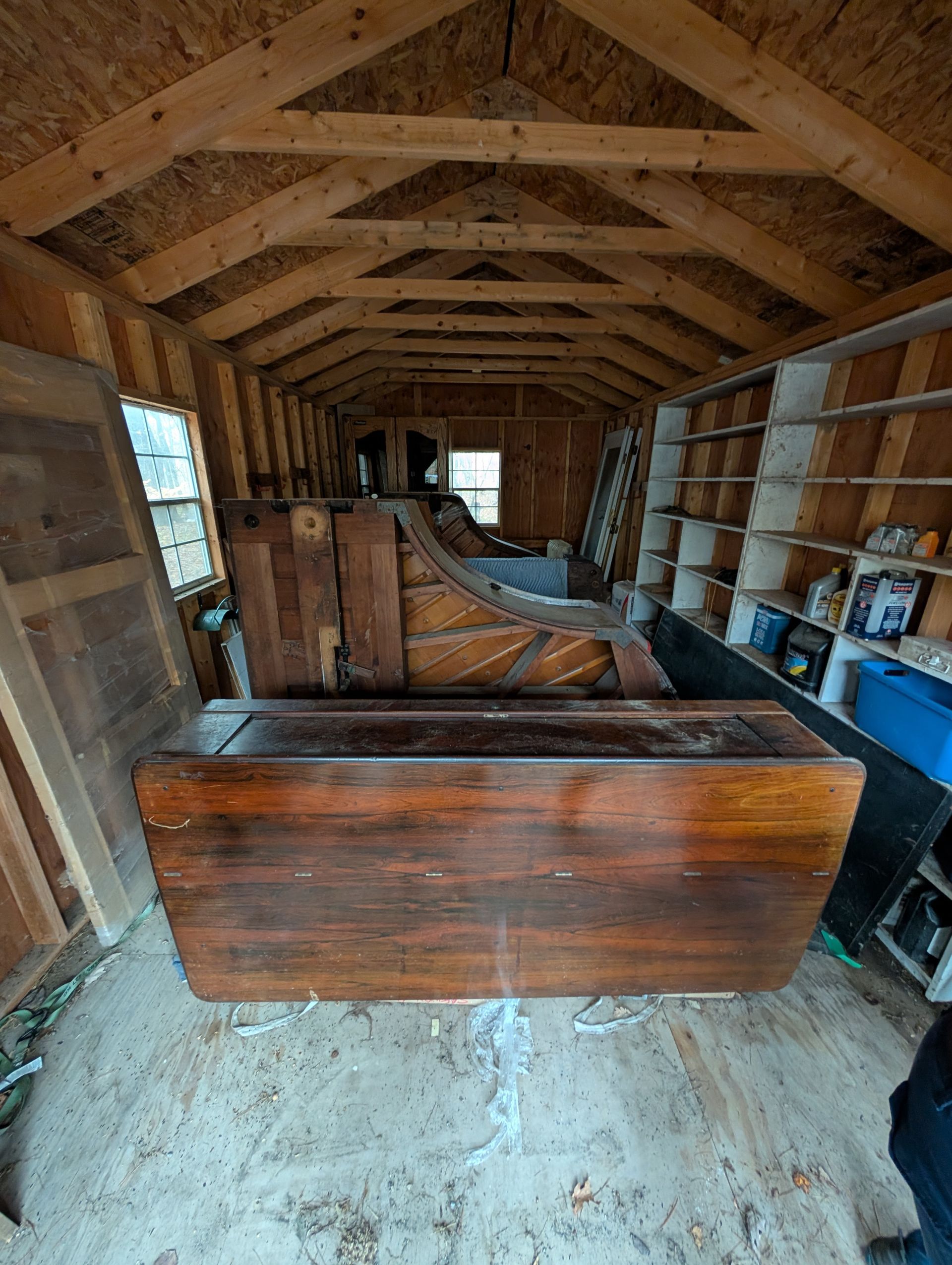 Inside a cluttered wooden garage, with a hand truck and various items.