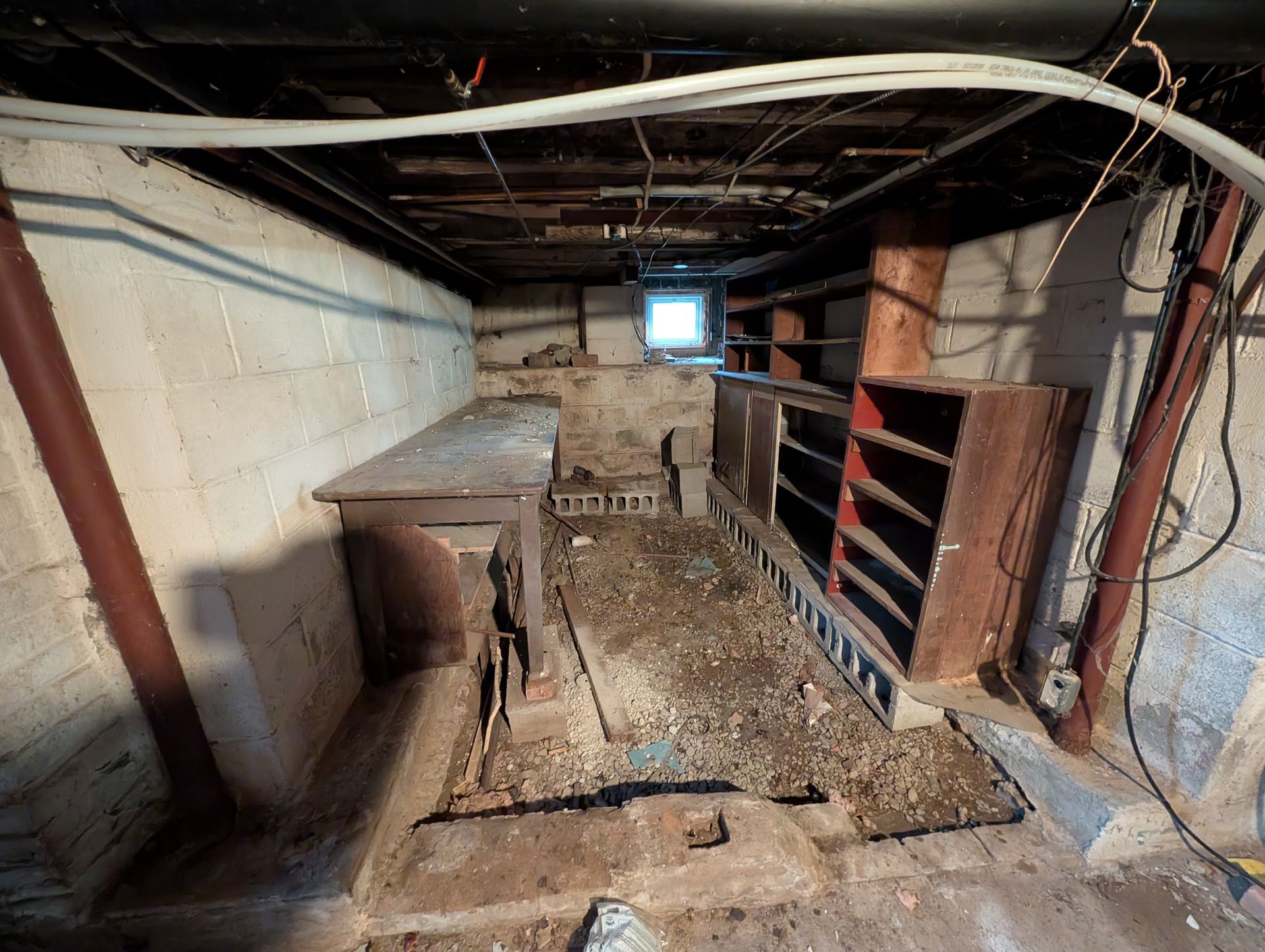 Basement interior with concrete walls, exposed pipes, and storage cabinets.