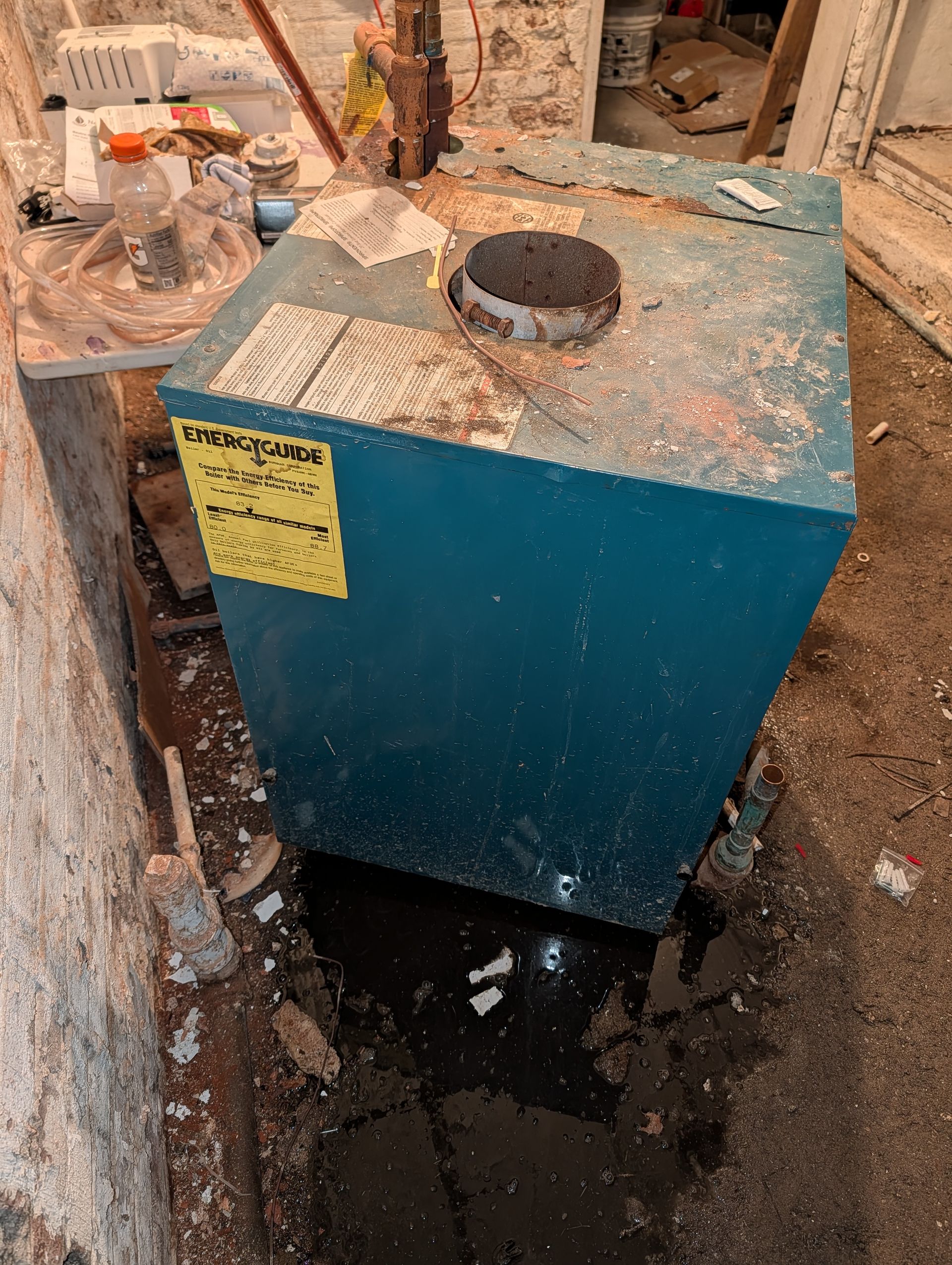 Blue furnace in a basement with water damage and debris.