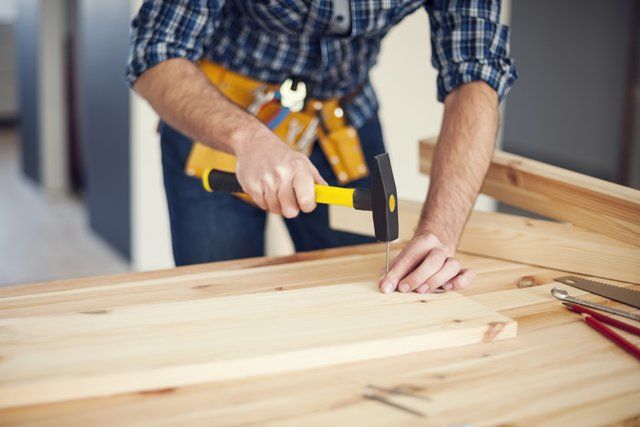 carpenter nailing a wood plank