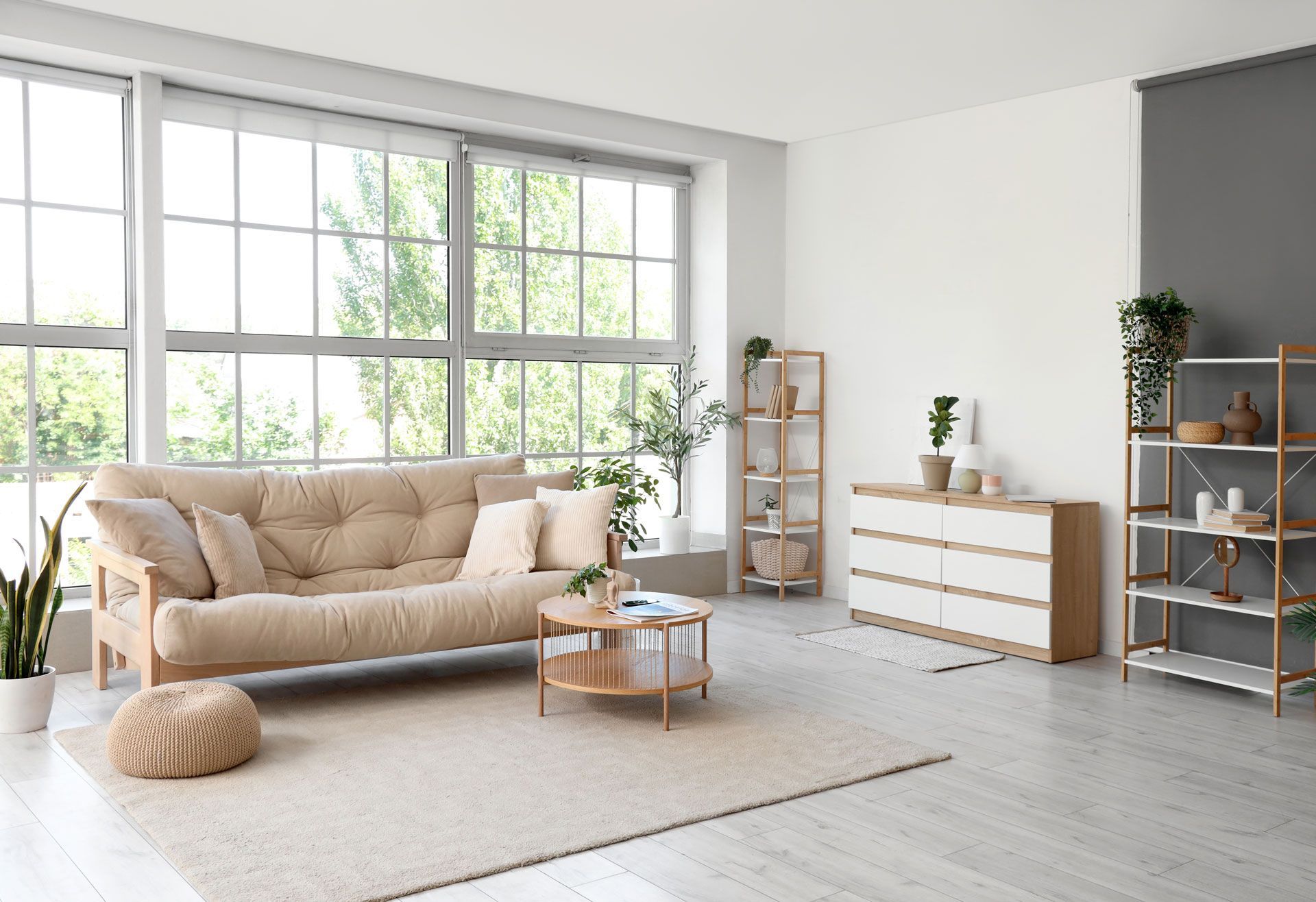 A living room with a couch , dresser , coffee table and lots of windows.