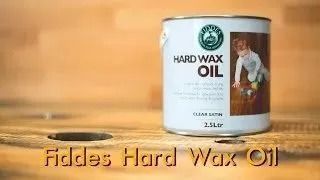 Fides Hard Wax Oil can on wooden surface with hole, warm orange background