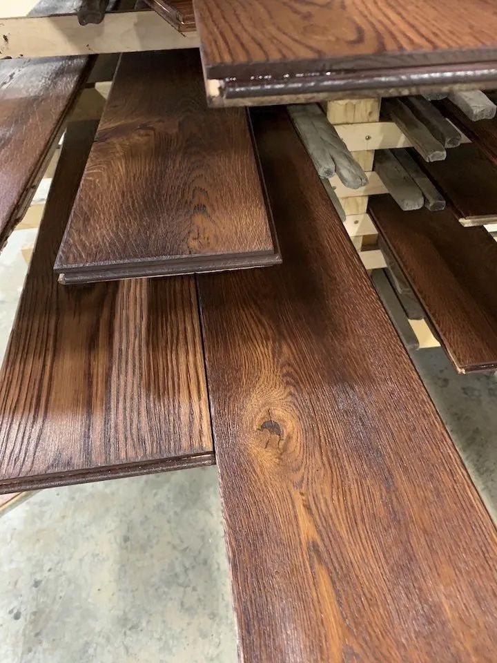 Stacked dark wood flooring planks on shelves in a warehouse or store aisle.