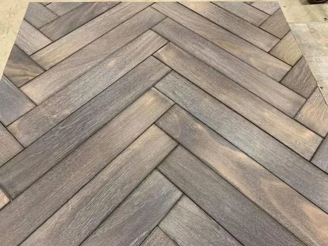 Chevron-patterned wood flooring in gray and tan tones with a herringbone-like design.