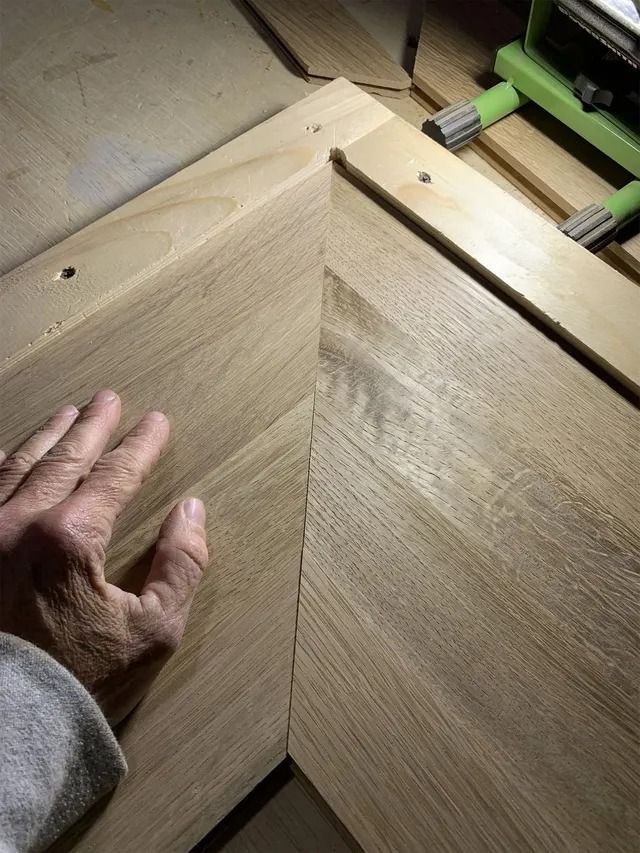 Hand sanding a wooden surface with a triangular grain pattern and a clamp at the top right
