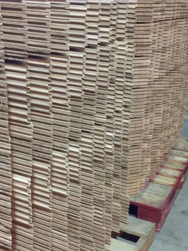 Tall stacks of beige cardboard sheets piled on red pallets in a warehouse