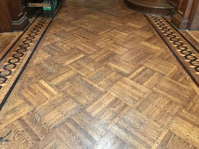 Parquet wood floor with a herringbone pattern and ornate border trim