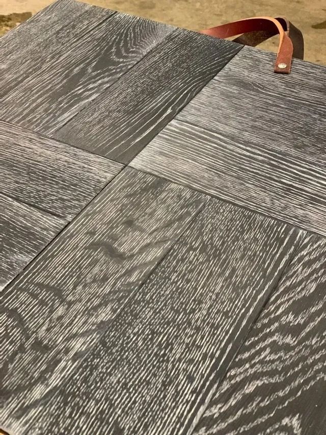 Gray patterned carpet tiles with a brown leather strap lying across the top edge.