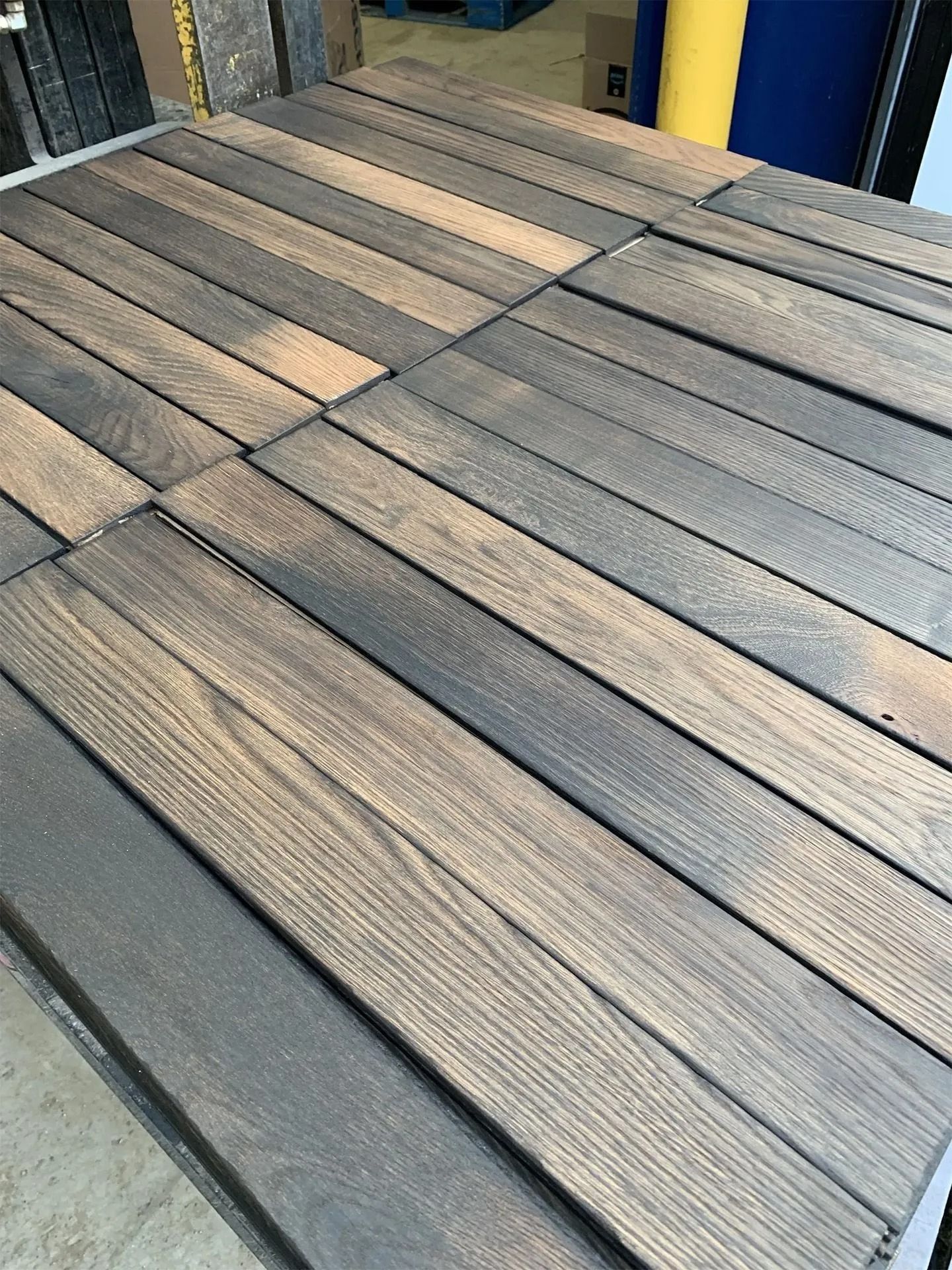Wooden deck tiles in a gray-brown checkerboard pattern, viewed from above