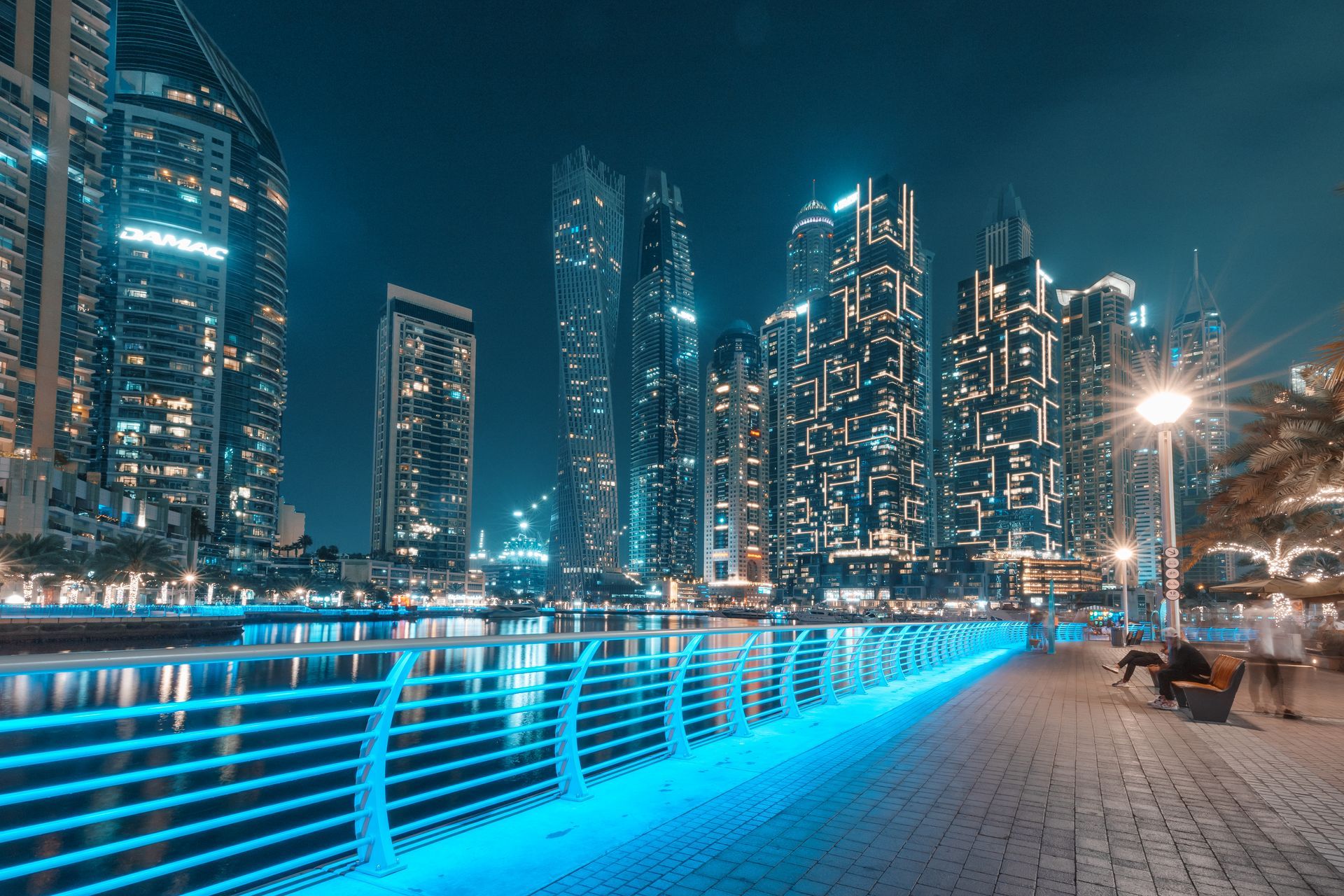 Night view of Dubai Marina with illuminated skyscrapers and waterfront promenade.