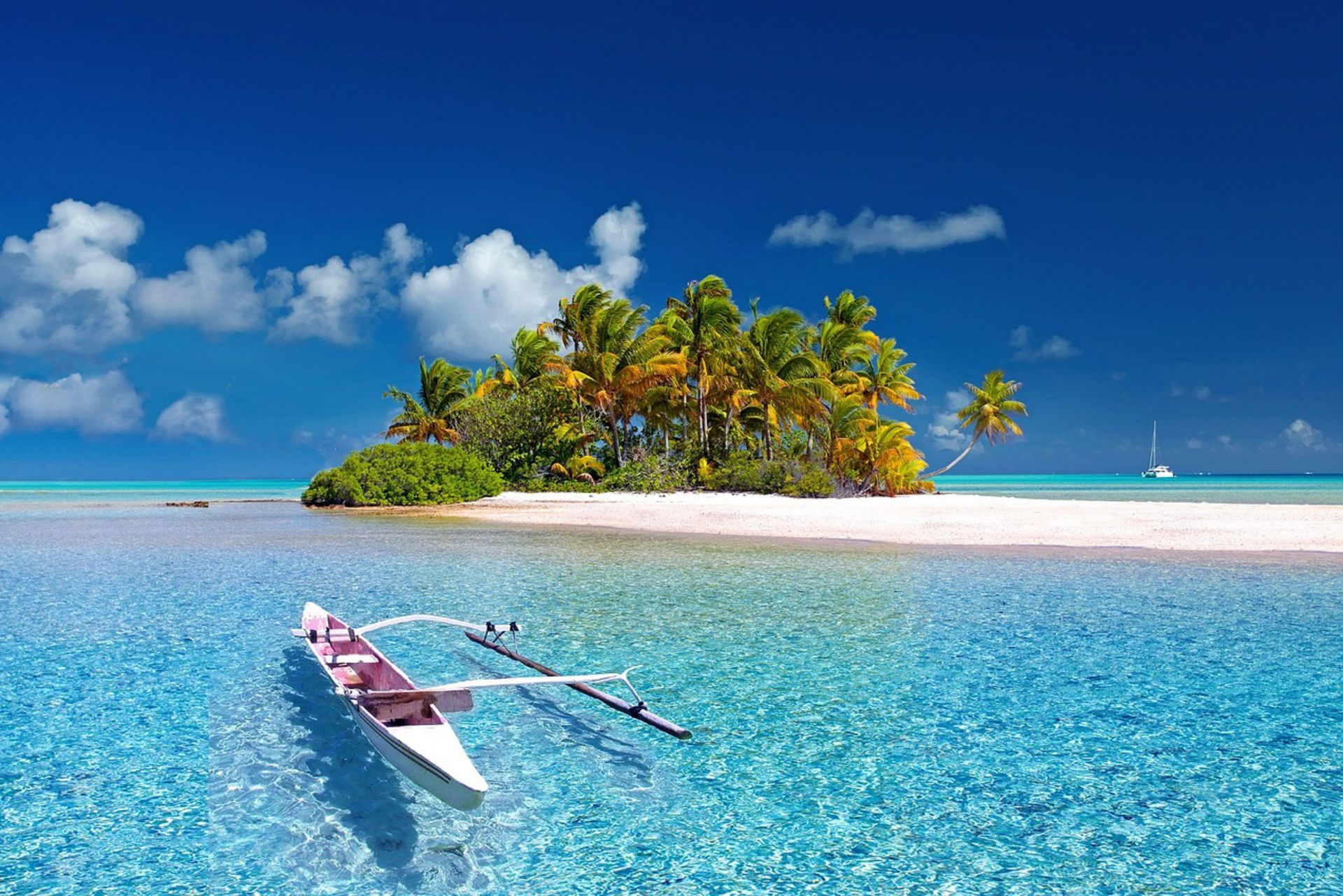 Small tropical island with palm trees and white sand, turquoise water, canoe.