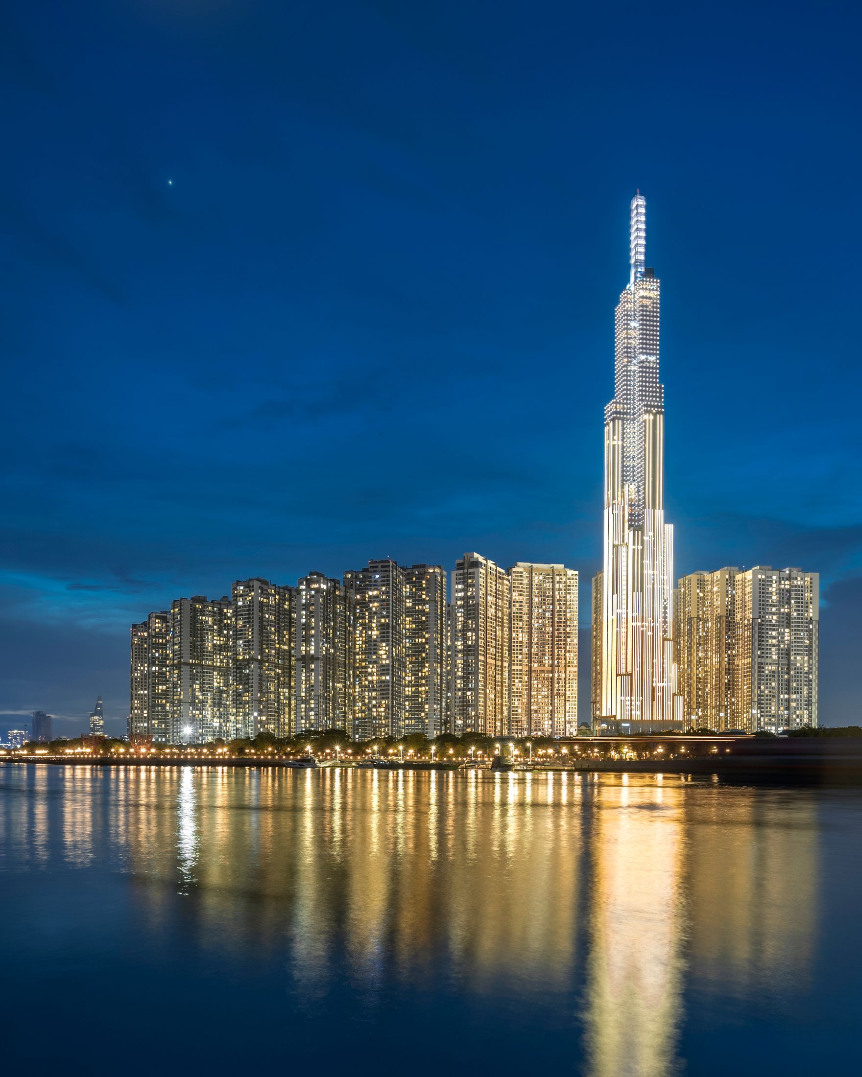 Night view of illuminated skyscrapers reflecting in calm water, Saigon, Vietnam.