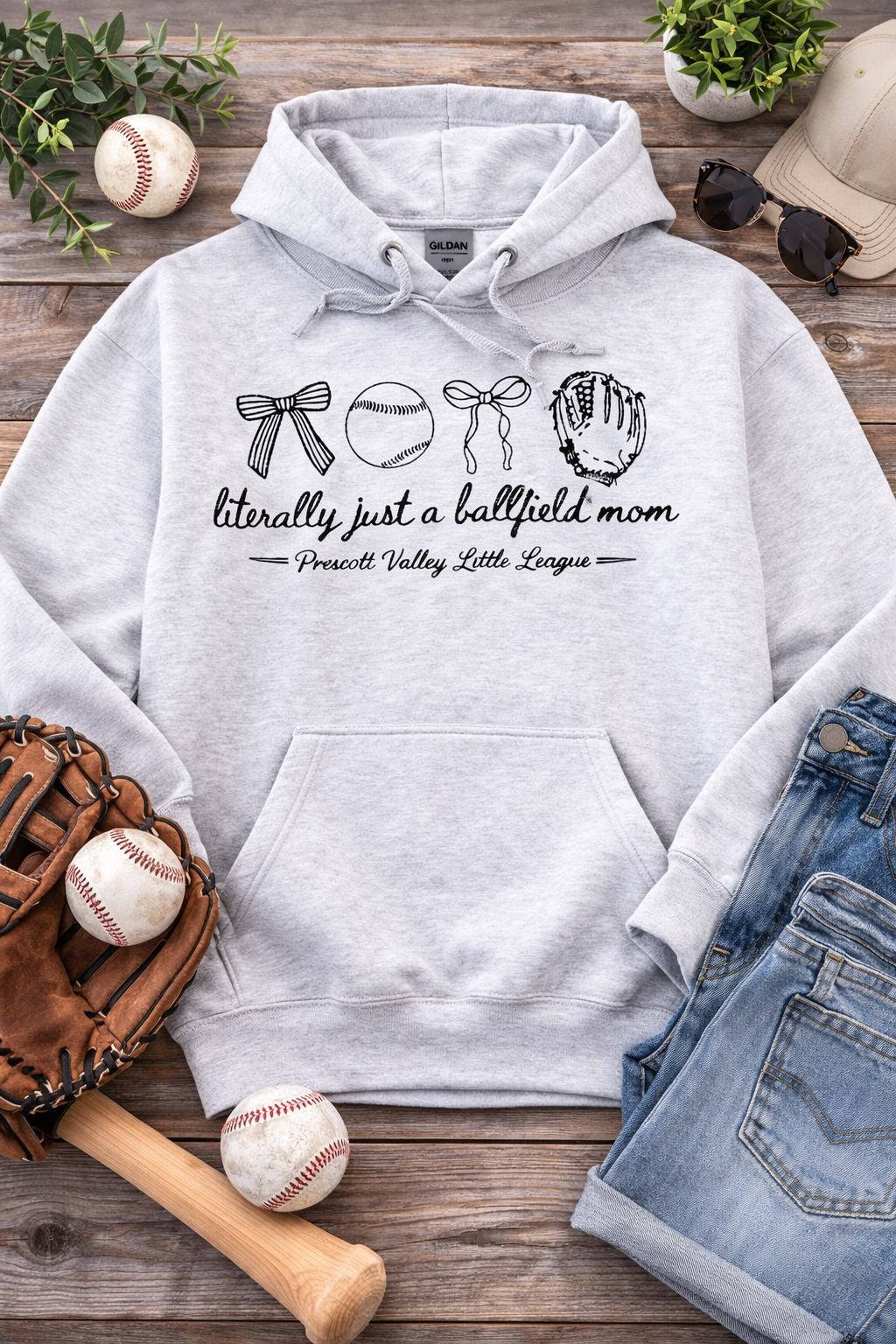 Light gray hoodie with text, baseball glove, balls, and a bat on a wood background.