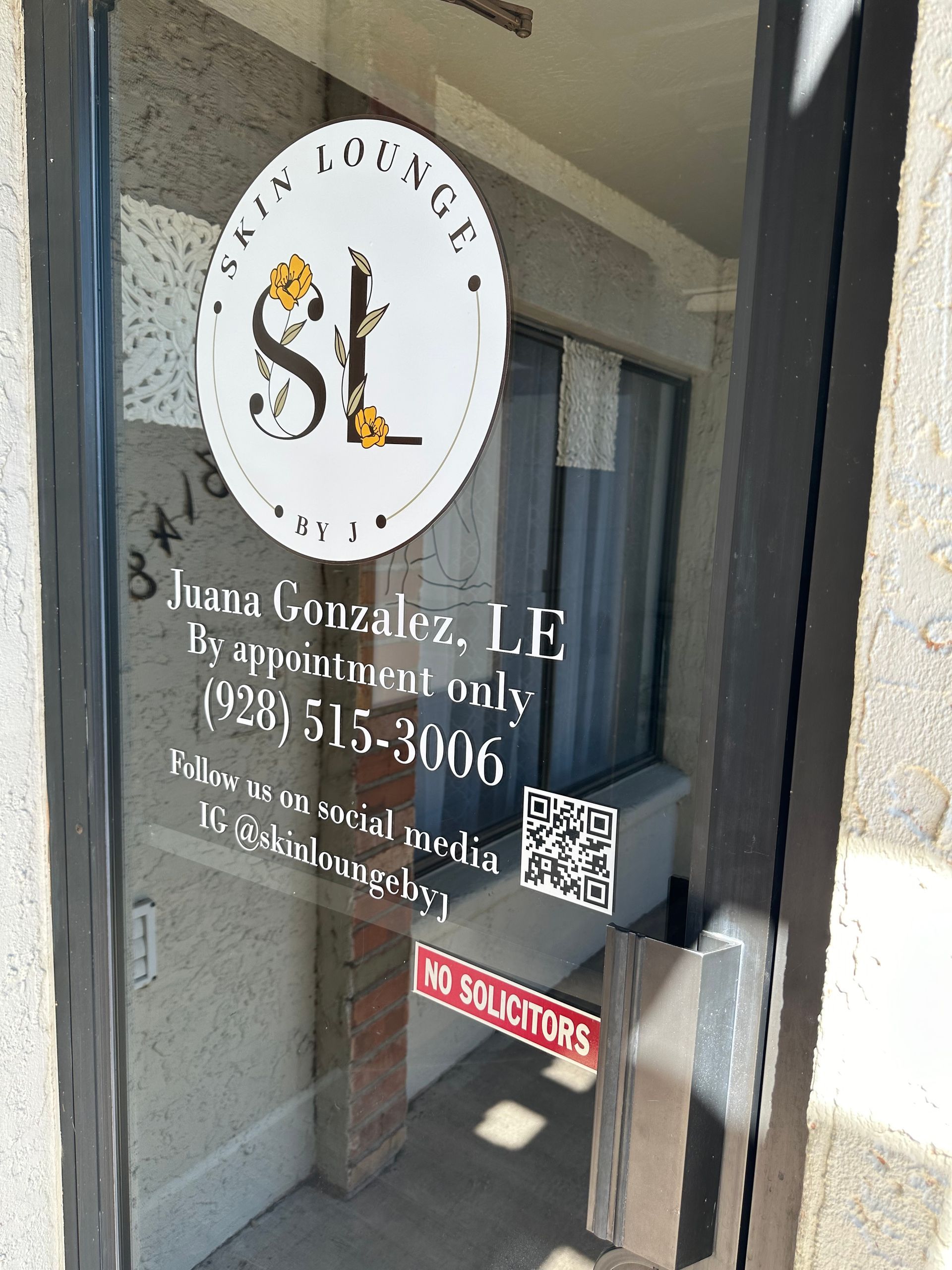 Glass door with a Skin Lounge sign and business information. Includes phone number and QR code.
