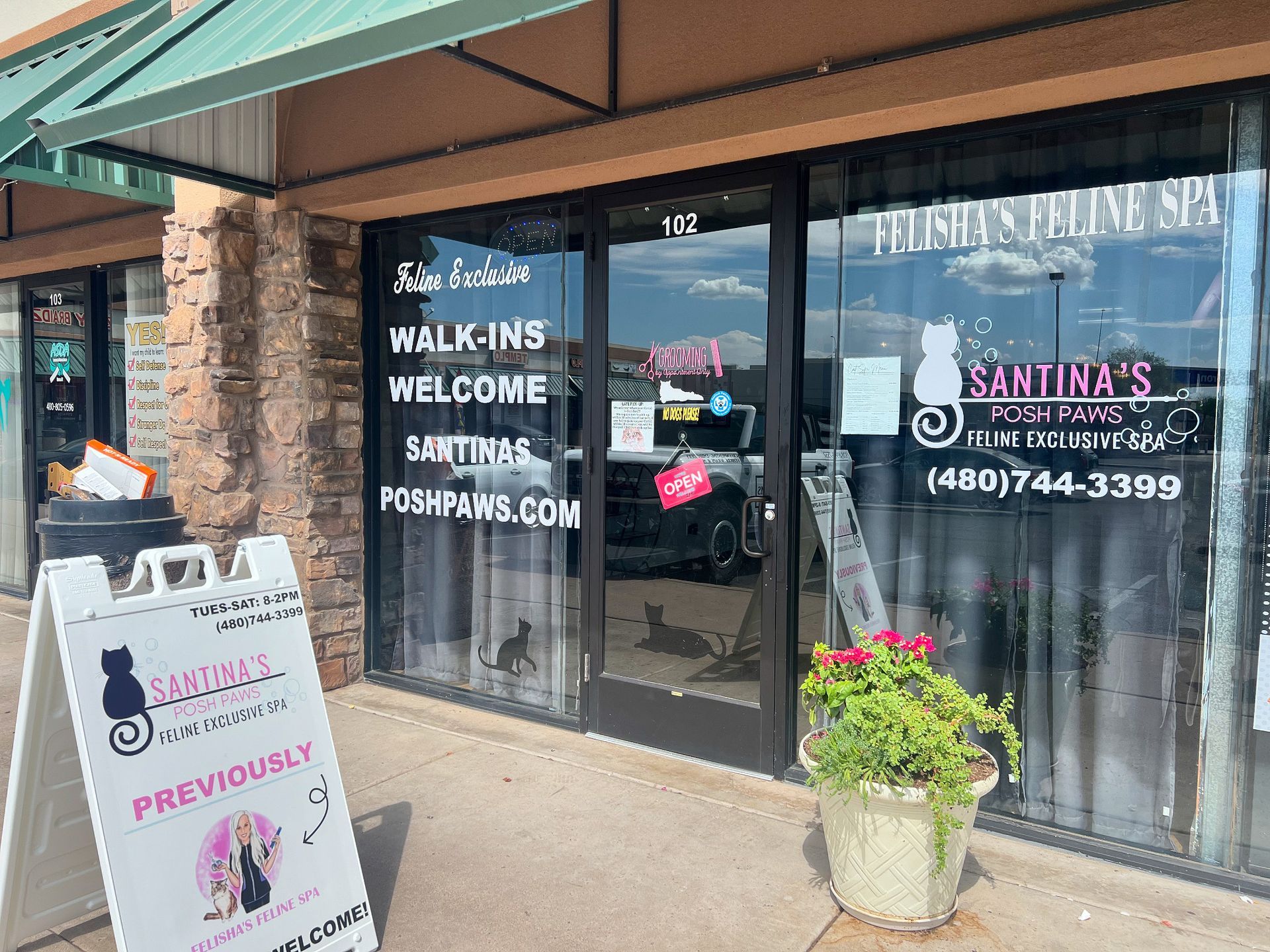 Exterior of Sarina's Posh Paws, a pet grooming spa. Entrance with glass door, sign: walk-ins welcome.